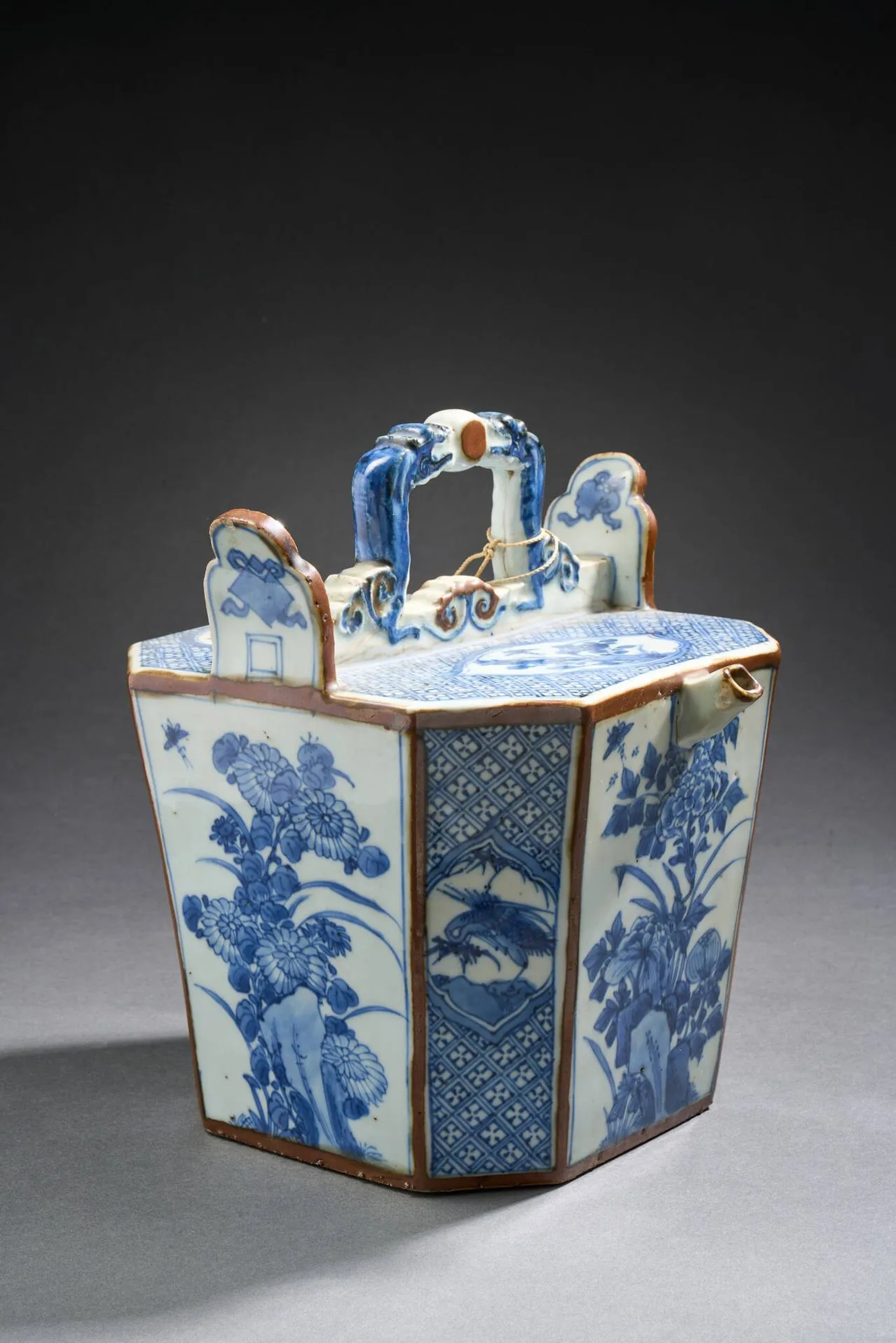 CHINE, fin du XIXe siècle Théière de section octogonale en porcelaine au décor bleu et blanc de végétaux et d'animaux Anses figurant des animaux fantastiques affrontés 23 x 17,5 x 17,5 cm Fels