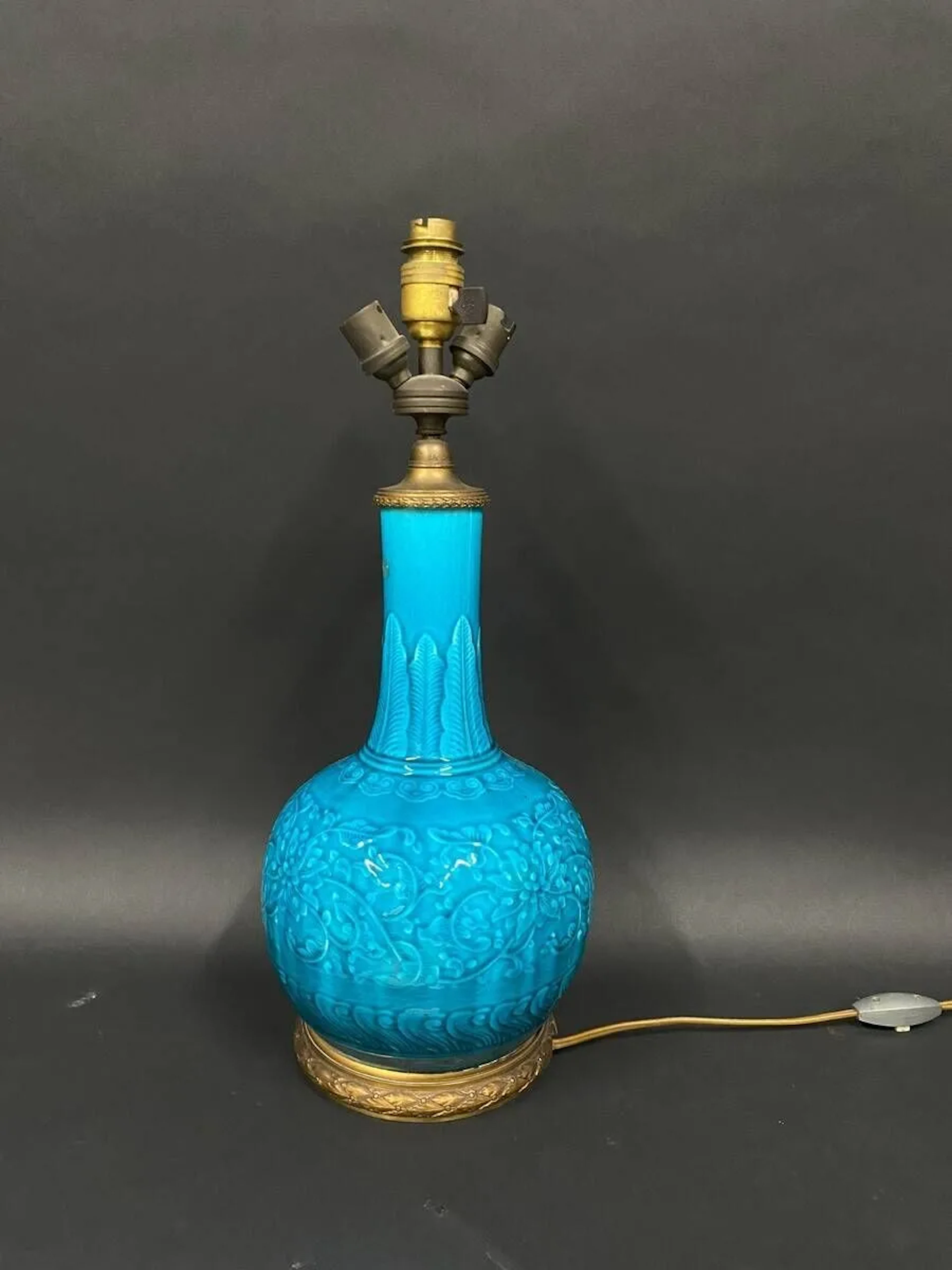 Théodore DECK (1823-1891) Lampe de table à trois lumières en céramique à corps sphérique et col cylindrique légèrement galbé. Décor en léger relief de fleurs dans des branchages dans un goût japonisant, émail turquoise. Base circulaire et bague supérieure en laiton. Signée à la base des initiales de l'artiste. Haut. 36 cm