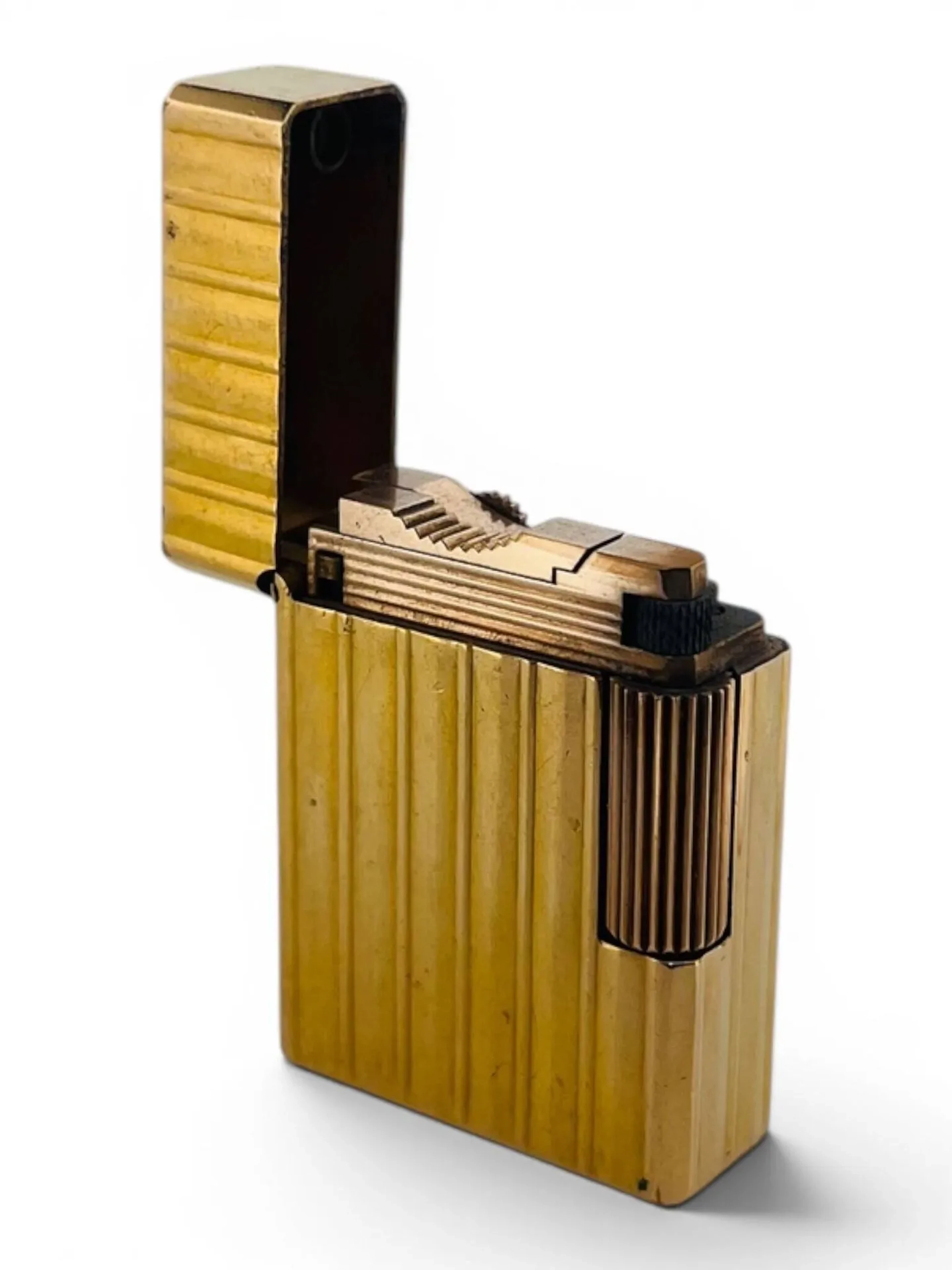 S.T. DUPONT Briquet standard petit modèle en métal doré à décor cannelé. Signé sur le dessous et numéroté K0813 Dim. 46 x 35 mm Rayures et chocs
