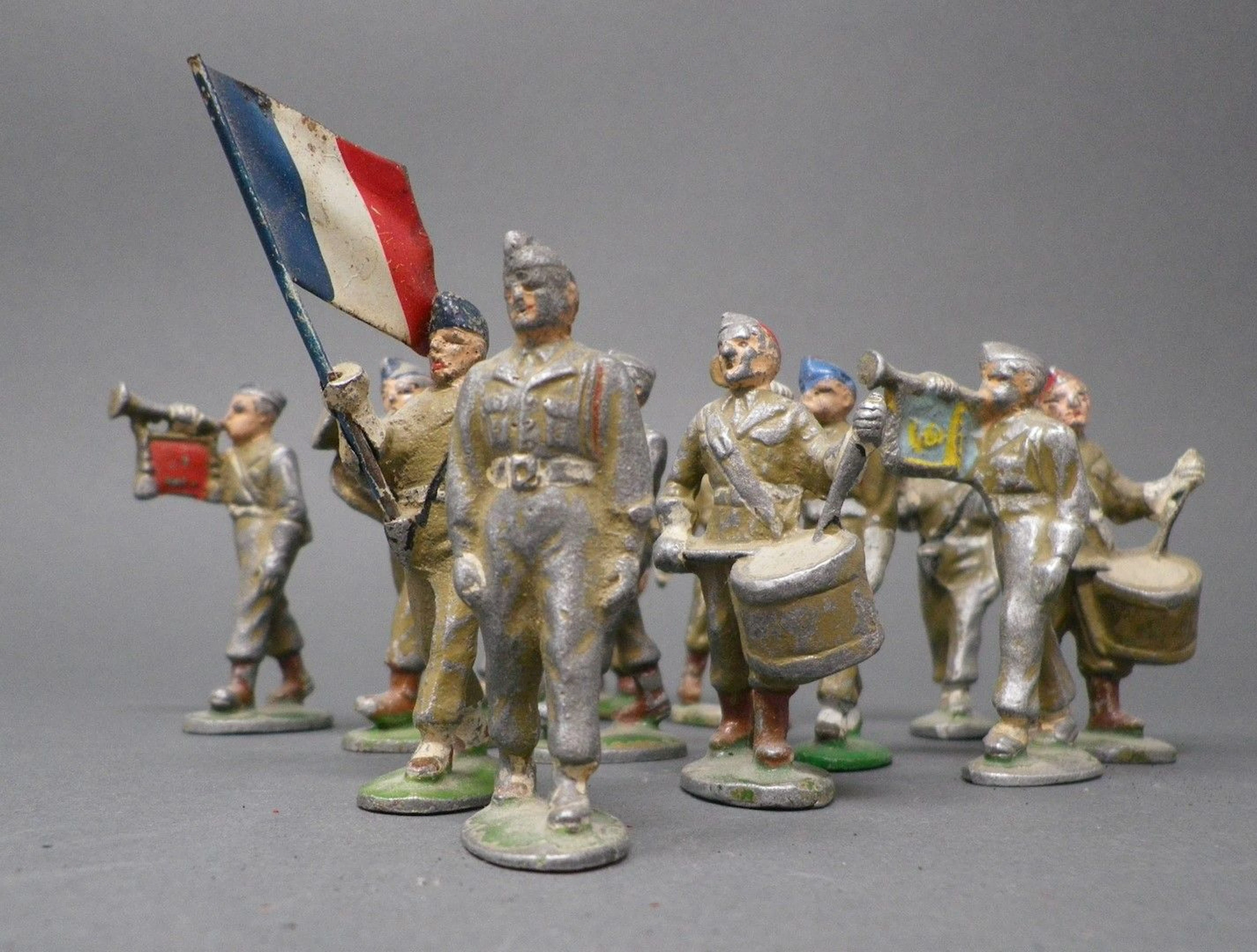 QUIRALU - Infanterie au défilé (1952-1960) Dix-huit figurines dont le chef de musique et les musiciens, reproduits p. 55 - Bibliographie : Les jouets Quiralu 1933-1964 - R. Alazet - J. Borsarello - H. Giroud - Ed° J. Granchet Paris. Jouets anciens pouvant présenter des manques de peinture, des chocs ou des manques, y compris pour les conditionnements éventuels. Vendus en l'état et sans réclamations.