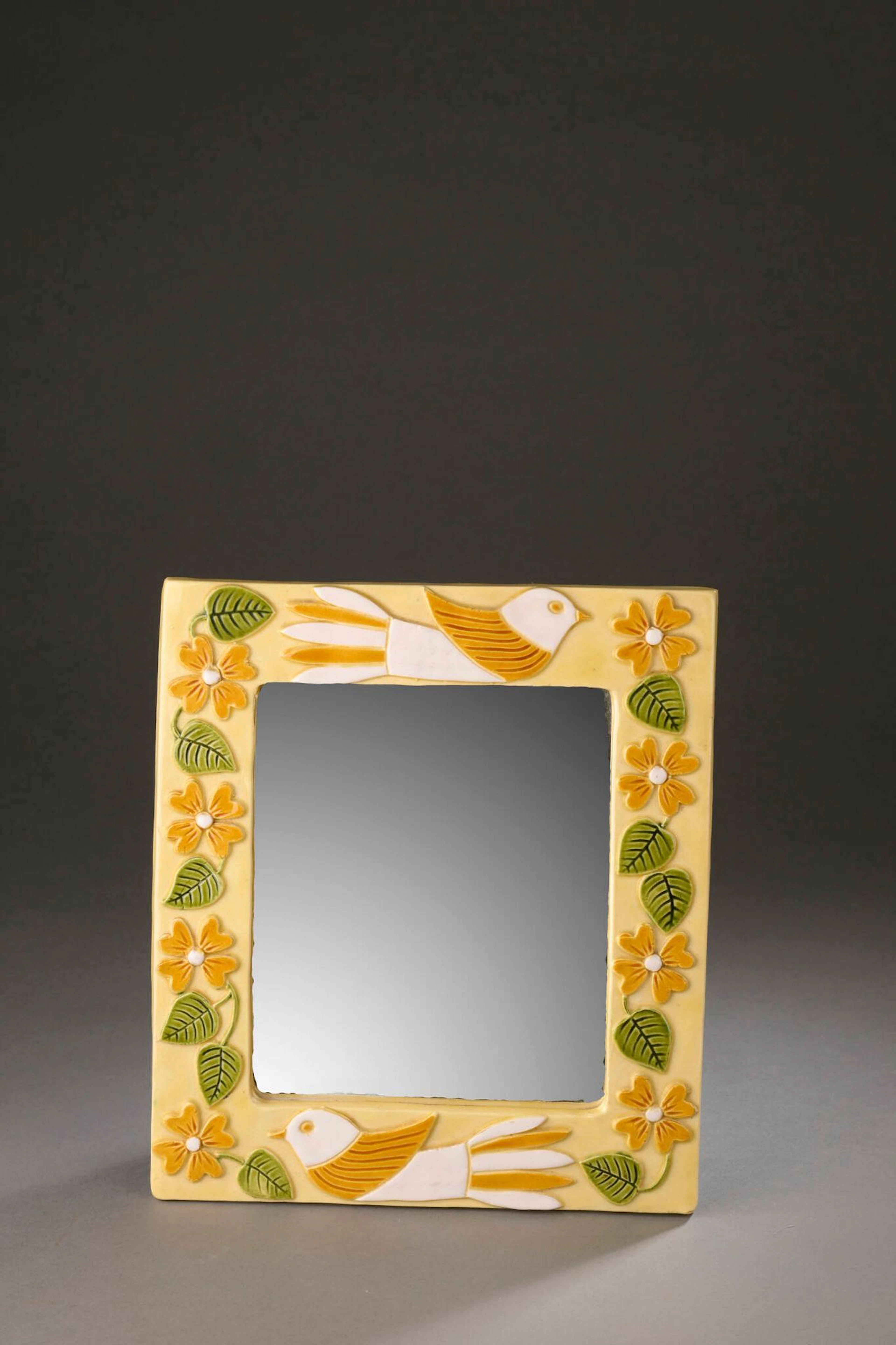 Mithé ESPELT (1923-2020) Miroir mural de forme rectangulaire modèle Polynésie, circa 1985 Épreuve en terre estampée et émaillée polychrome à décor d’oiseaux et de fleurs H. : 29 cm. – L. : 25.5 cm. (Quelques défauts d’émaillage) Bibliographie : - Antoine Candau, Mithé Espelt - le luxe discret du quotidien, Edition Odyséee, 2020, modèle similaire reproduit p. 190