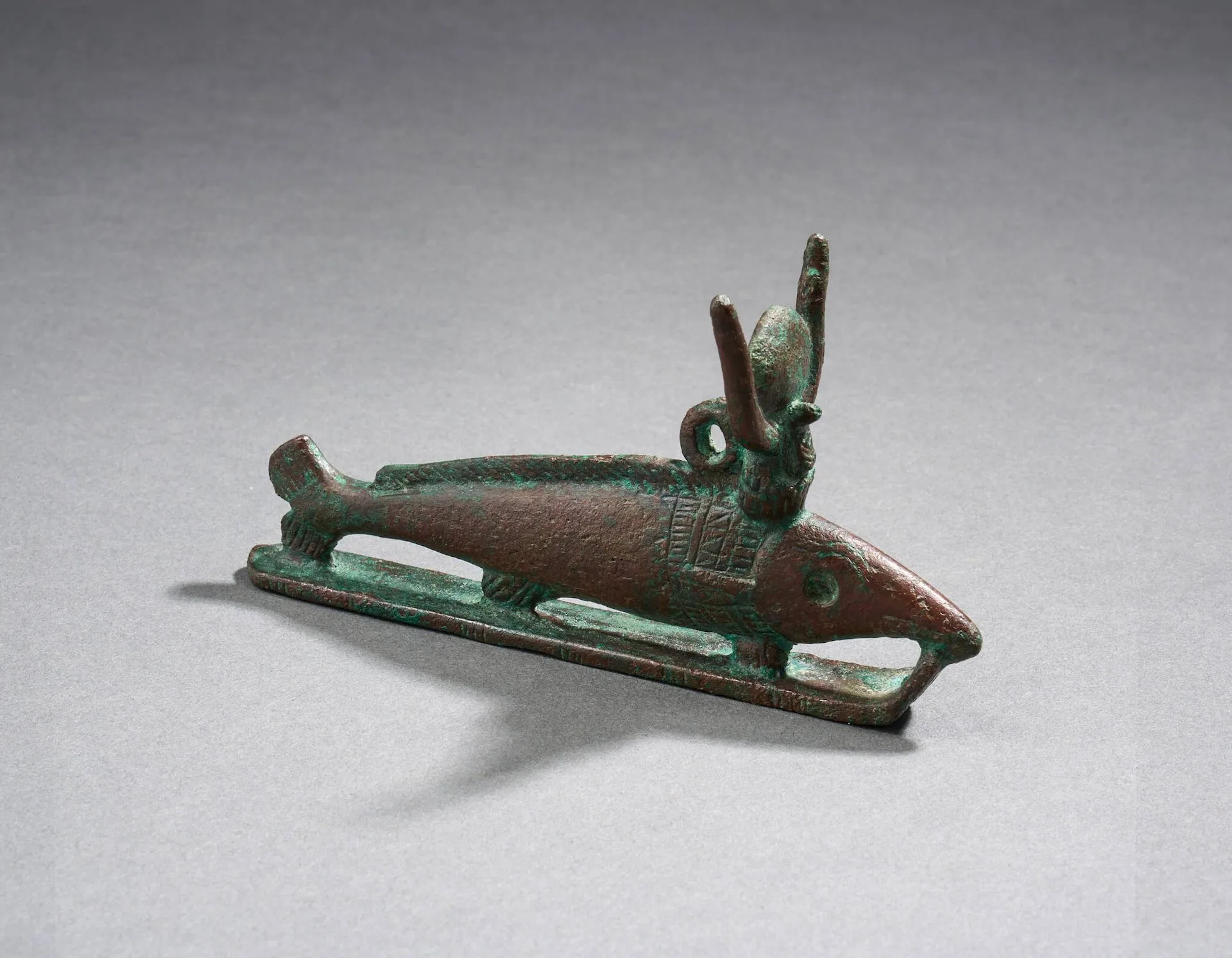 Statuette représentant le poisson oxyrhynque coiffé des cornes hathoriques. Il est finement gravé d’un collier et repose sur un traîneau. Bronze à patine marron sombre. Égypte, Basse Époque (664–332 av. J.-C.) ou ptolémaïque (332–30 av. J.-C.) Hauteur : 7 cm ; Longueur : 12,5 cm