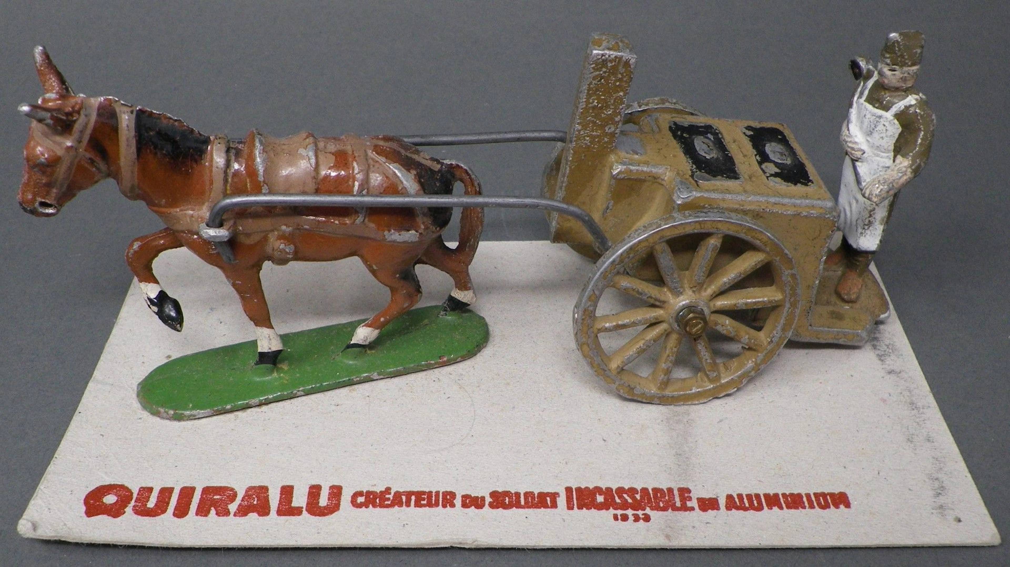 QUIRALU - Corvée de quartier (1933-1940) Cuisine roulante, sur son socle en carton QUIRALU créateur du soldat incassable en aluminium, modèle proche reproduit p. 51 - Bibliographie : Les jouets Quiralu 1933-1964 - R. Alazet - J. Borsarello - H. Giroud - Ed° J. Granchet Paris. Jouet ancien pouvant présenter des manques de peinture, des chocs ou des manques, y compris pour les conditionnements éventuels. Vendu en l'état et sans réclamations.