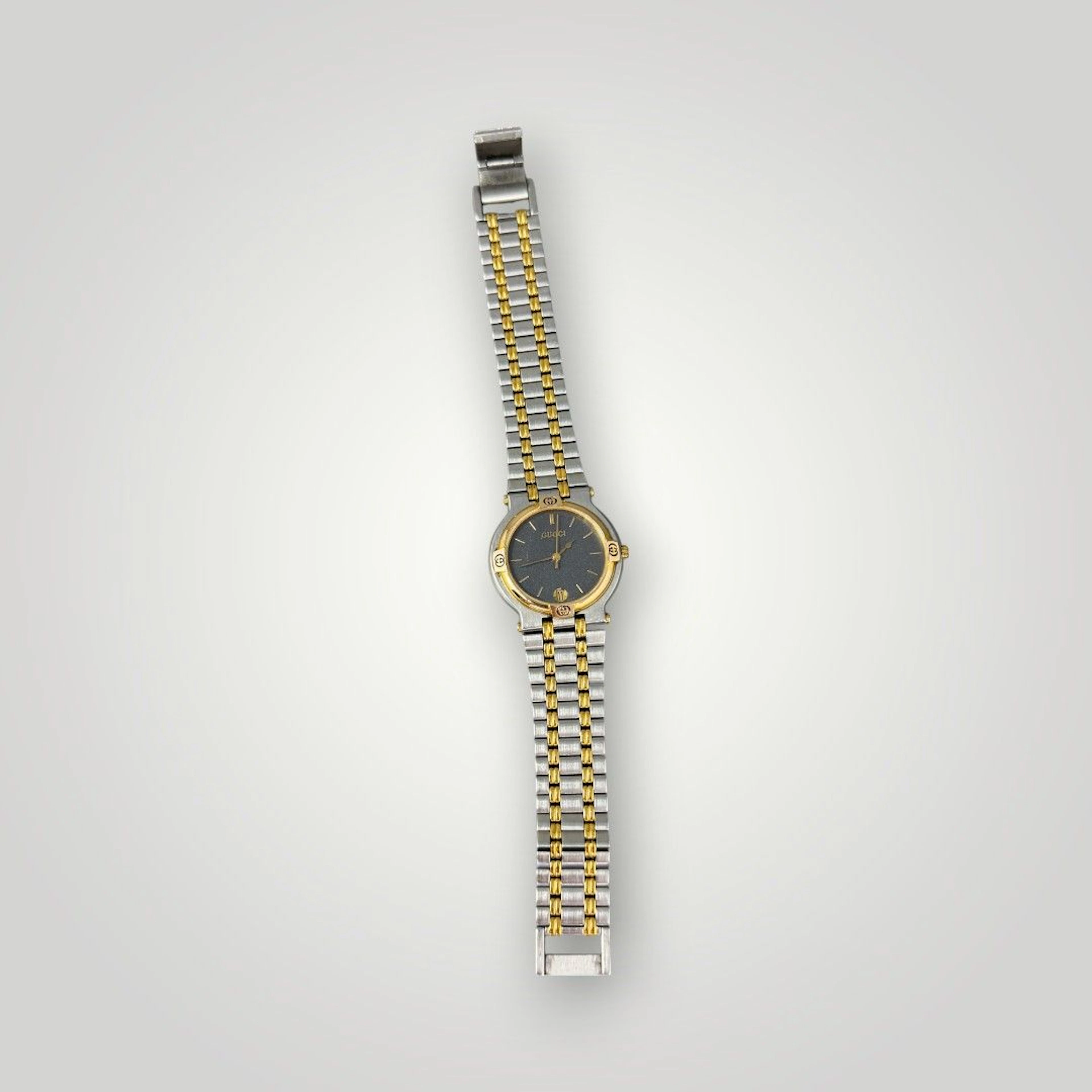GUCCI Montre bracelet en acier et métal doré, cadran à guichet dateur Fermoir siglé Fonctionnement non garanti L: 20 cm