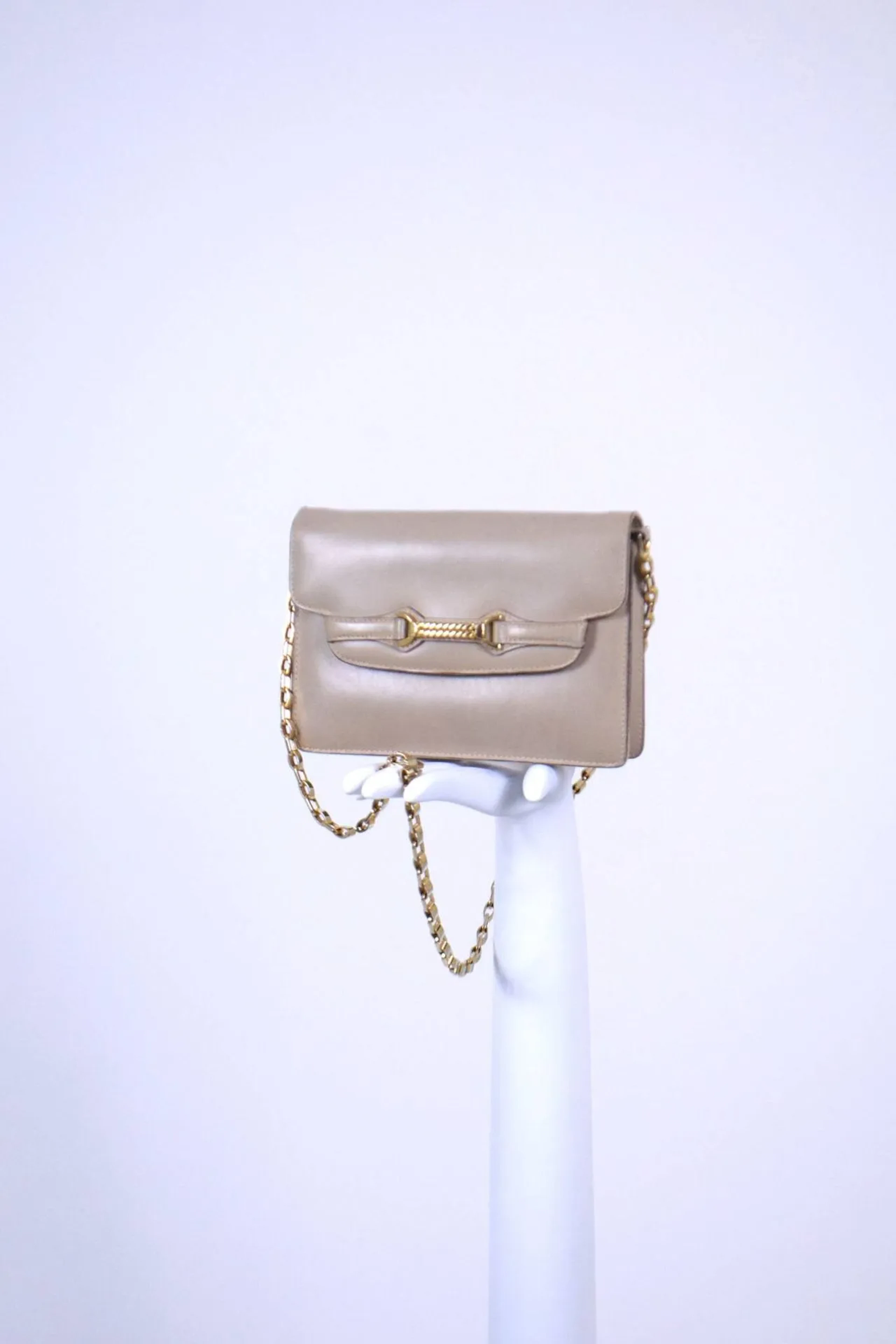 GUCCI Circa fin 1970 Sac porté bandouière ou épaule en cuir mastic à bijouterie dorée orné d'un mors stylisé central sur rabat et d'une chaine amovible assortie. Légères usures, pattine de la couleur, fermoir grippé. Dimensions : 14 x 20 x 4 cm
