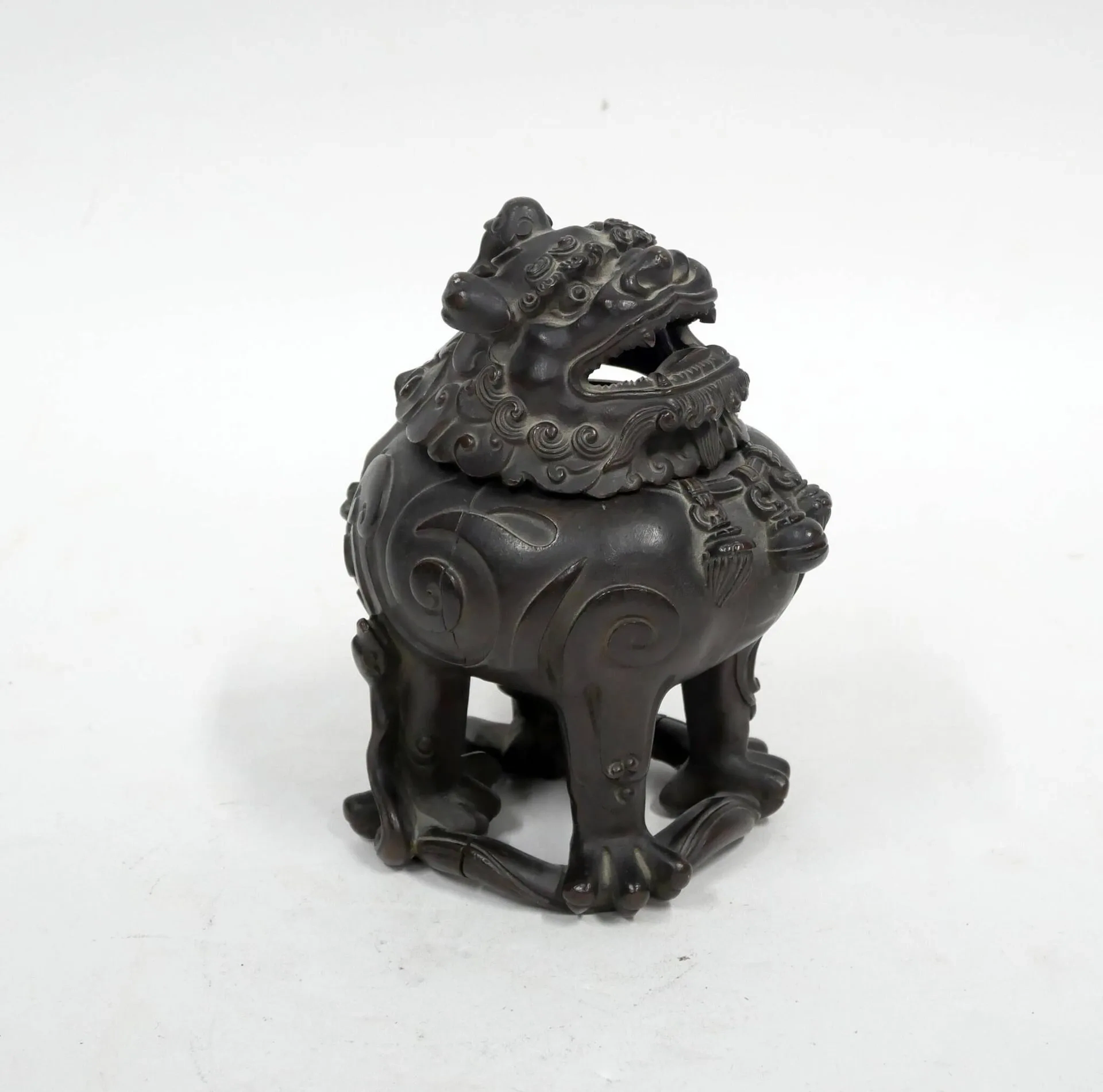CHINE - XVIIIe siècle Brûle-parfum en forme de bixie en bronze à patine brune, représenté debout sur un ruban, portant un collier orné de clochettes. La tête formant couvercle, la gueule ouverte laissant sortir la fumée. (Corps en deux parties). H. 16 cm