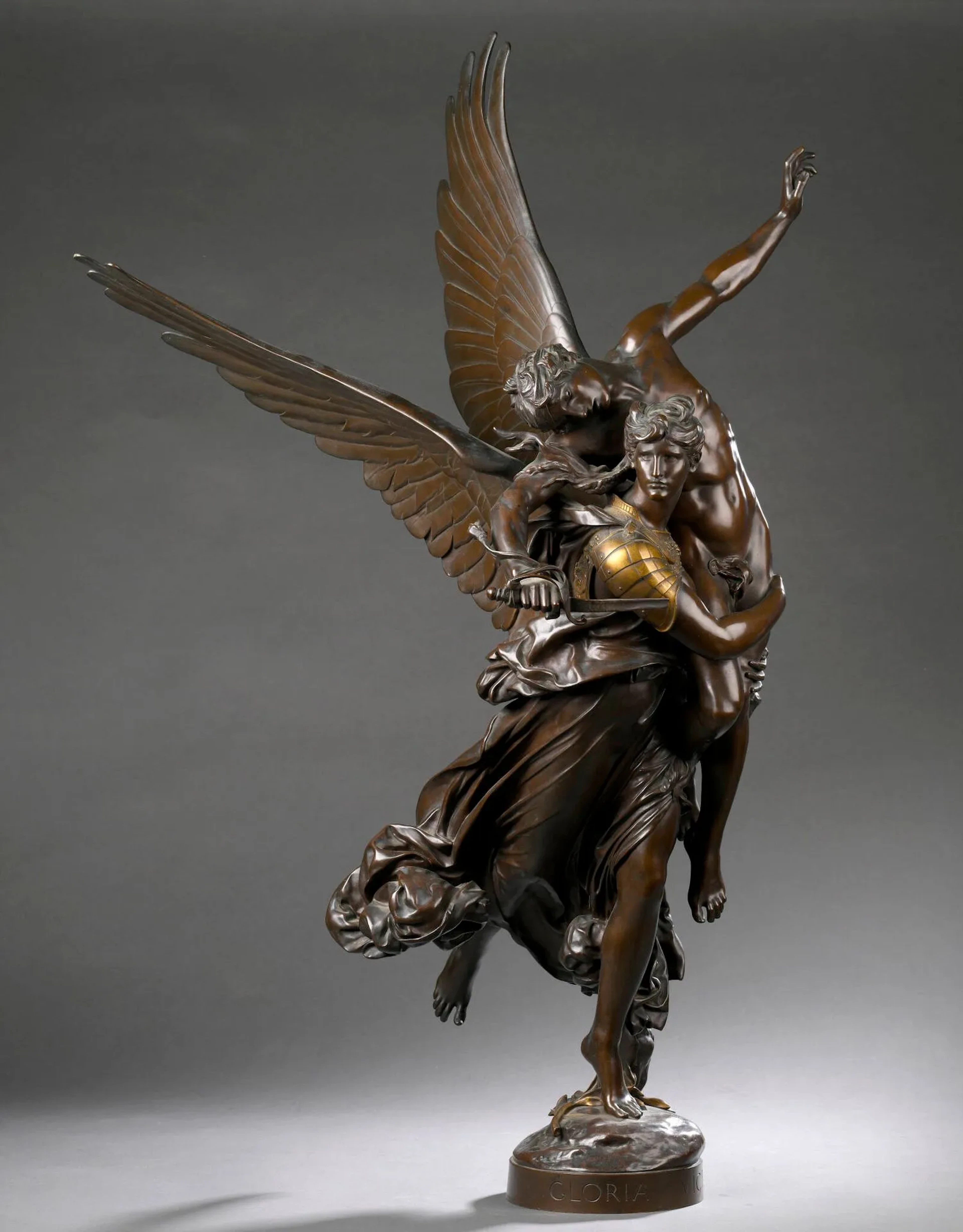 MERCIÉ Antonin, 1845-1916, Gloria victis, groupe en bronze à patines brune et dorée, F. BARBEDIENNE Fondeur, réduction mécanique A. Collas (glaive légèrement tordu, petites traces d'usures à la patine), sur la terrasse : A. MERCIÉ et les marques du fondeur, dessous : n°321 Z en creux, Ht. : 92,5 cm. Présenté au Salon de 1874, où il reçoit la médaille d'honneur, Gloria Victis compte parmi les réalisations majeures d'Antonin Mercié. Conçue dans le contexte de l'après-guerre de 1870, la composition montre une allégorie ailée de la Gloire soutenant un soldat vaincu tenant son épée brisée. Par son titre même, l'œuvre rend hommage aux combattants français tombés lors du conflit et s'impose rapidement comme l'un des symboles du souvenir patriotique de la Troisième République. L'accueil réservé à cette sculpture fut tel que plusieurs municipalités sollicitèrent l'autorisation d'en ériger des versions monumentales. Un exemplaire fut notamment installé à Niort en 1881, tandis que d'autres furent érigés à Bordeaux, Châlons-sur-Marne ou Cholet. Ces commandes contribuèrent à faire de Gloria Victis l'une des représentations commémoratives les plus célèbres de la guerre franco-prussienne.