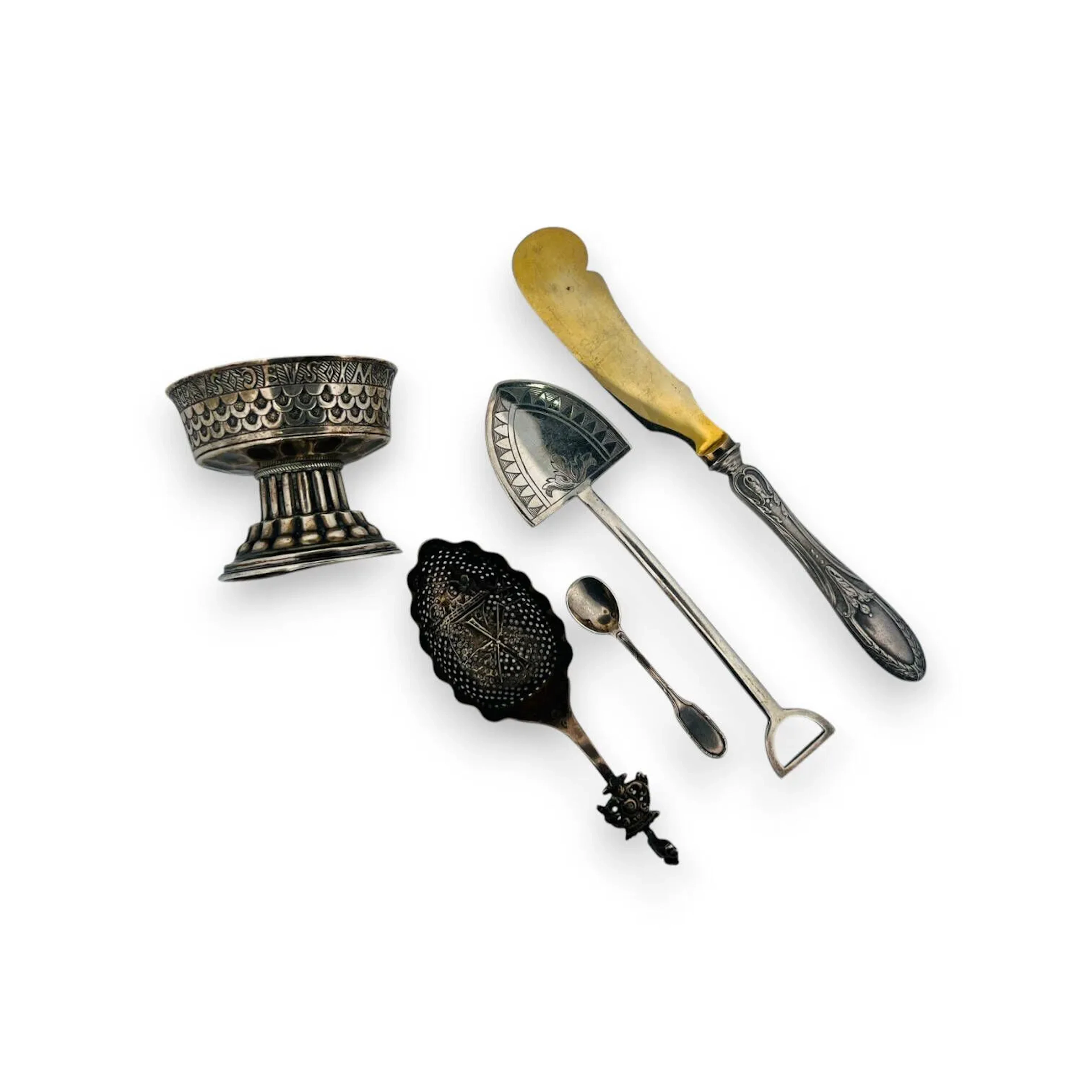 Lot comprenant: - Petite coupe sur piédouche en argent (925) à décor au repoussé de de motifs géométriques, la coupe à base martelée et portant des inscriptions religieuses gravées. Chester, 1906 Poids: 72,3 gr - Passe-thé en argent (835), le cuilleron à décor d'un moulin et le manche appliqué d'un lion emblème des Pays-Bas. Pays-Bas, XXème, Poids: 21,5 gr -Cuillère à moka en argent (925) modèle filets rubannés. Titre: poinçon minerve Poids: 6,7 gr - Objet décoratif en métal argenté stylisant une pelle, le cuilleron à décor ciselé d'un fleuron et de motifs géométriques. Angleterre, XXème siècle Long. 15,5 cm - Couteau à fromage en métal argenté et la lame en métal doré. Long. 19,2 cm