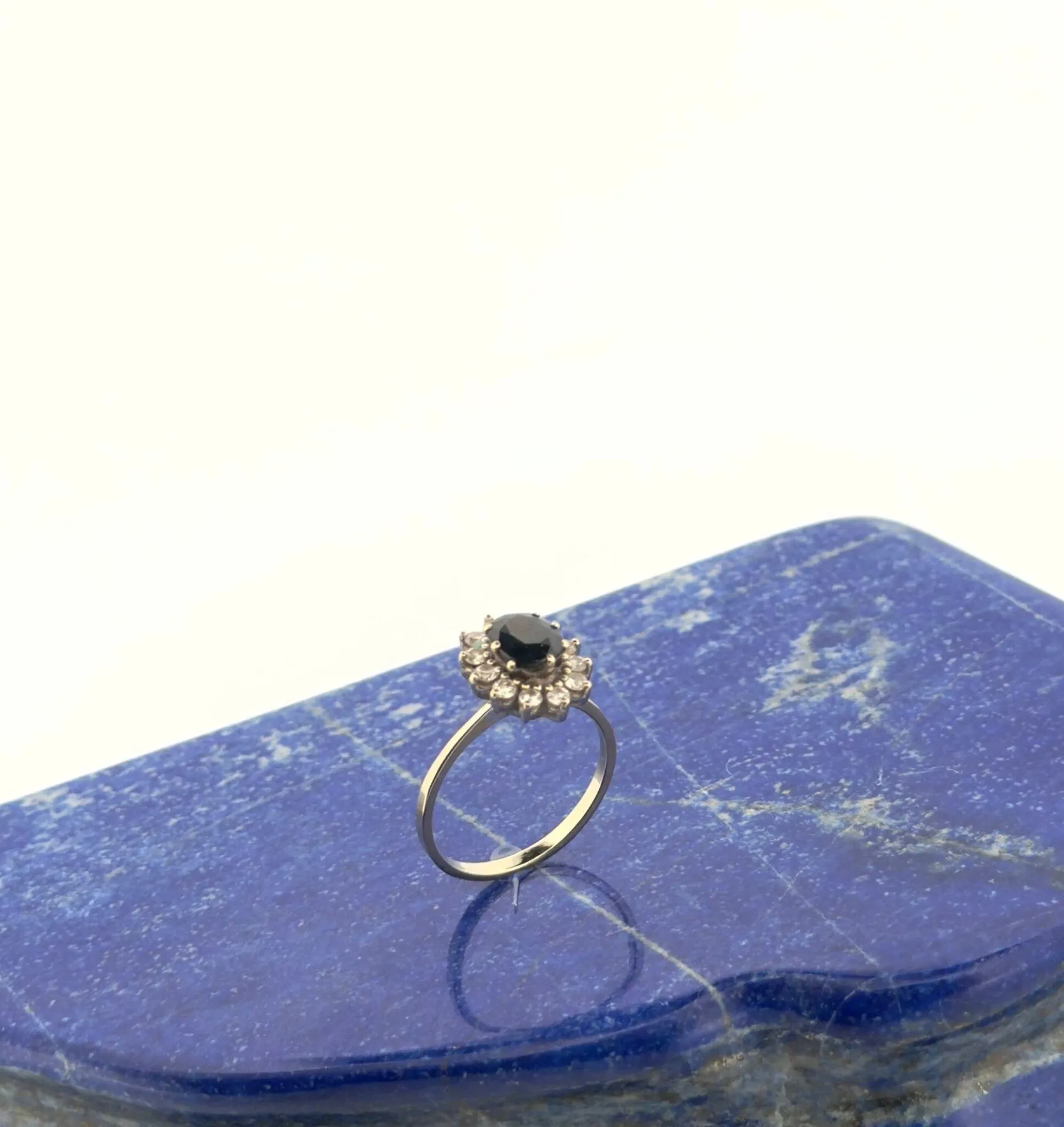 Bague marguerite en or gris 18K (750) sertie d'un saphir ova - Lot 177 Bague marguerite en or gris 18K (750) sertie d'un saphir ovale dans un entourage de brillants. Tour de doigt : 55.5 - Poids brut : 3.46 g. (égrisures)