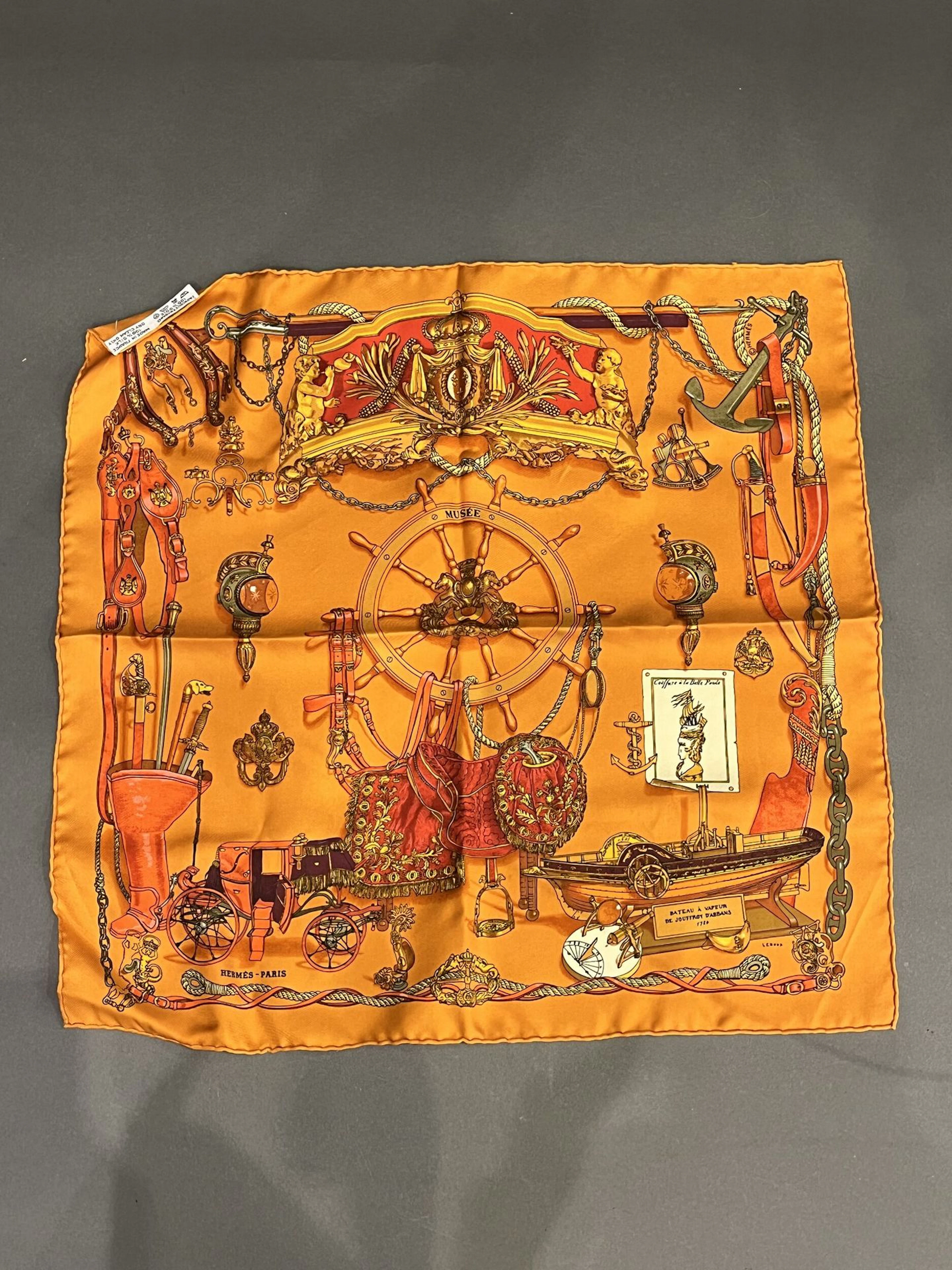 HERMES Petit foulard gavroche en tuile de soie, titre "Musée", fond orange Bon état dimensions : 45 x 45 cm.