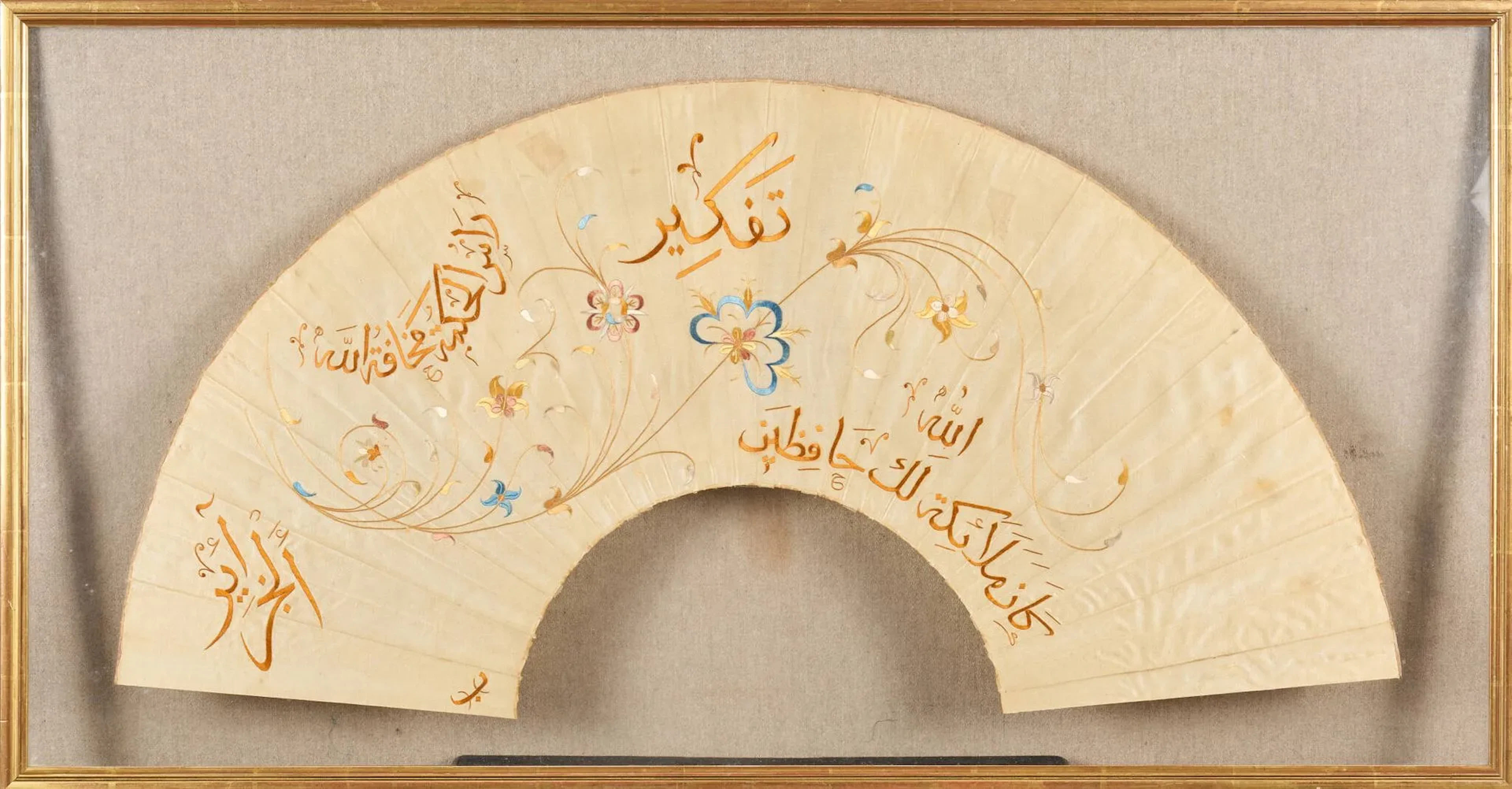 Feuille d’éventail en soie brodée, Algérie, situé à Alger XIXe siècle Feuille d’éventail en soie grège à décor brodé de fils de soie polychromes d’une longue tige florale sinueuse et d’inscriptions religieuses en arabe thuluth. Le texte dit : « Pensée ». « Dieu ». « Les anges te protègent ». « La plus grande des sagesses est la crainte de Dieu ». Suivent le nom d’Alger (« al-Jaza’ir) et la lettre « ba », possible initiale de l’artiste. Présenté déplié sans son armature sous verre encadré. H. max : 38 cm : L. : 76,5 cm Quelques taches et rousseurs, de l’adhésif au dos. Un exemple similaire (Galerie Le Curieux, Saint Ouen sur Seine) avec sa monture en nacre et sa boîte d’origine titrée au nom de la maison Duvelleroy, à Londres, laisse penser que cette feuille de soie brodée à Alger avait été montée en éventail à Londres par le même éventailliste, vers 1890.