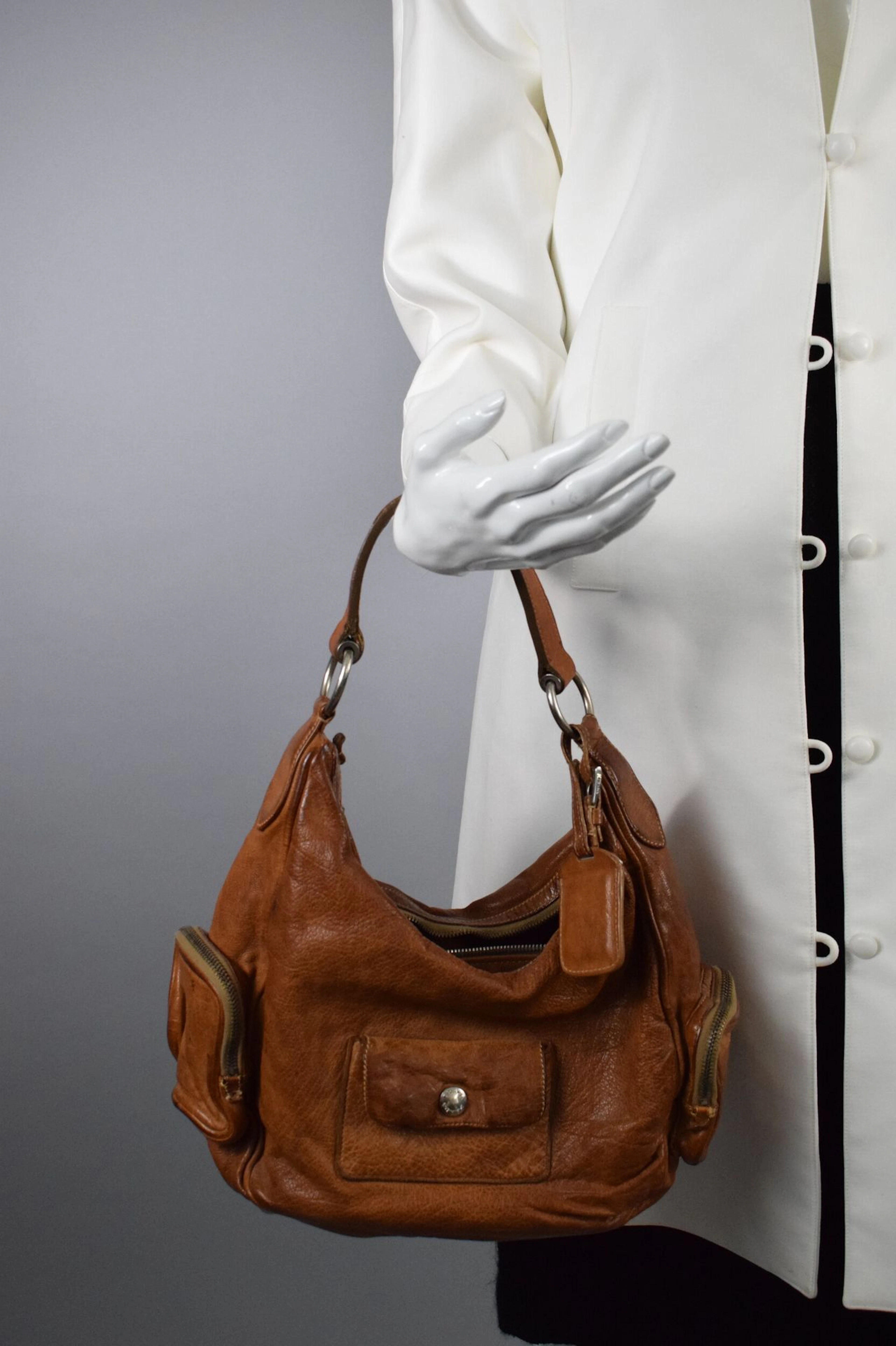 PRADA Sac porté main ou épaule en cuir naturel. Grande poche interne, plusieurs petites poches externes. Usures, traces, salissures. Dimensions : 20 cm x 33 cm x 11 cm