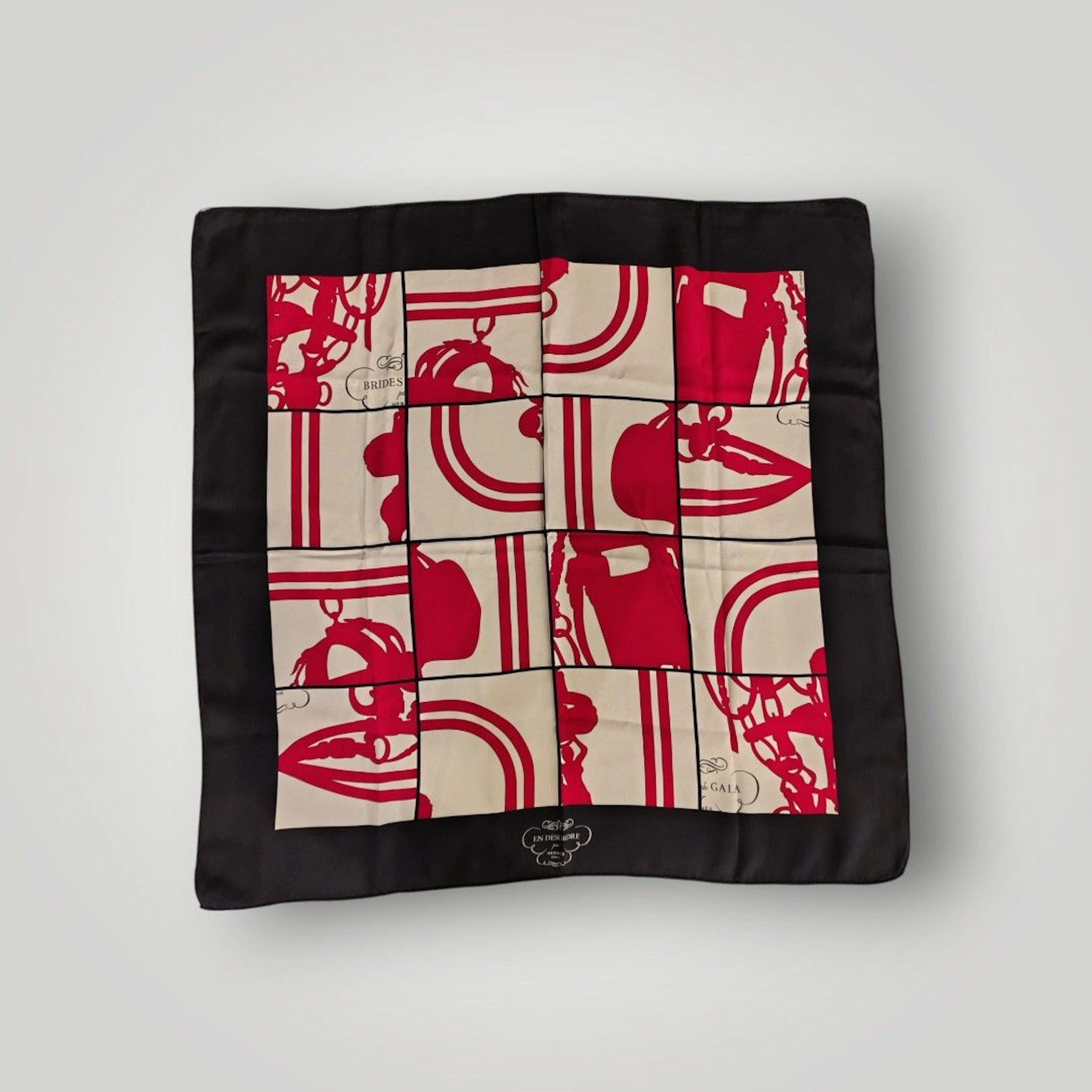 HERMES Petit foulard en twill de soie titré "En désordre" à bordure noires. Petites tâches et fils tirés. Avce sa boite. 68 x 68 cm.