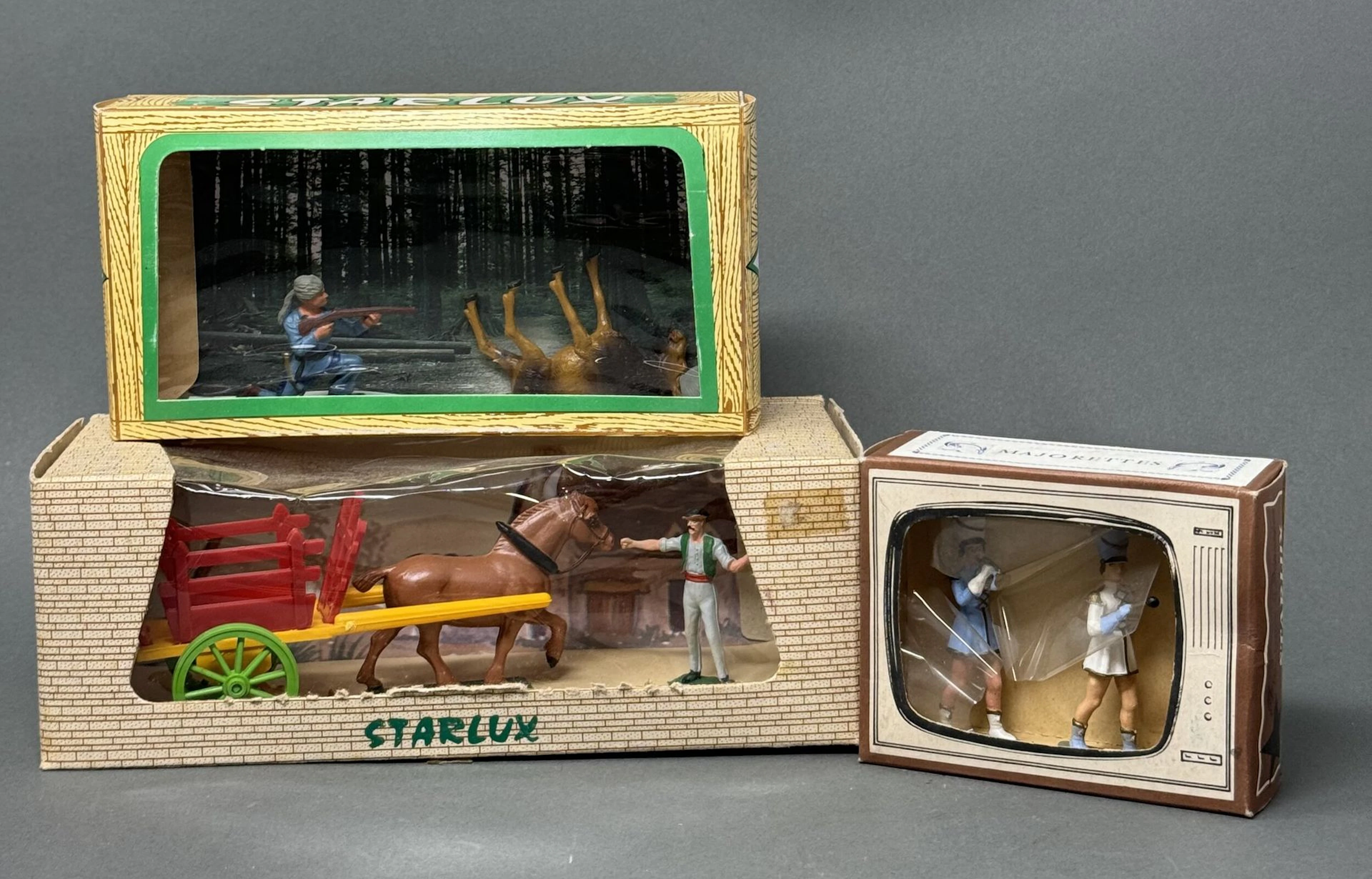 STARLUX Réunion de quatre pièces : - indien à cheval sous blister - deux majorettes dans leur boîte simulant une télévision (acc.) - coffret série " O " un trappeur visant un élan - coffret charrette fourragère Jouets anciens pouvant présenter des manques de peinture, des chocs ou des manques, y compris pour les conditionnements éventuels. Vendus en l'état et sans réclamations.