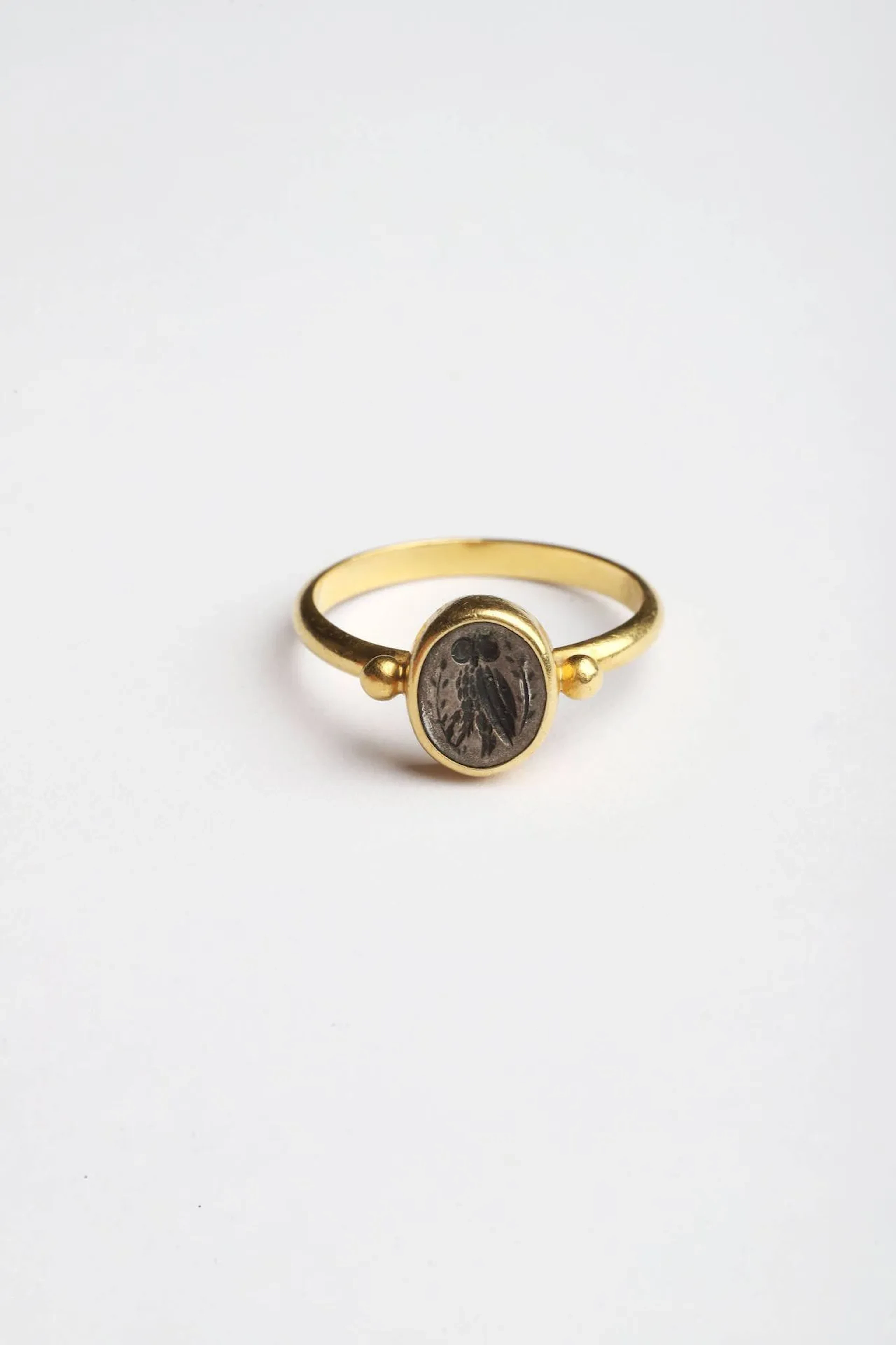 Bague en or (750 millièmes) de style grec antique à chaton ovale sertissant une intaille sur argent gravée d’une chouette stylisée. Grèce, XXe siècle. TDD : 53. Poids brut : 4,2 g