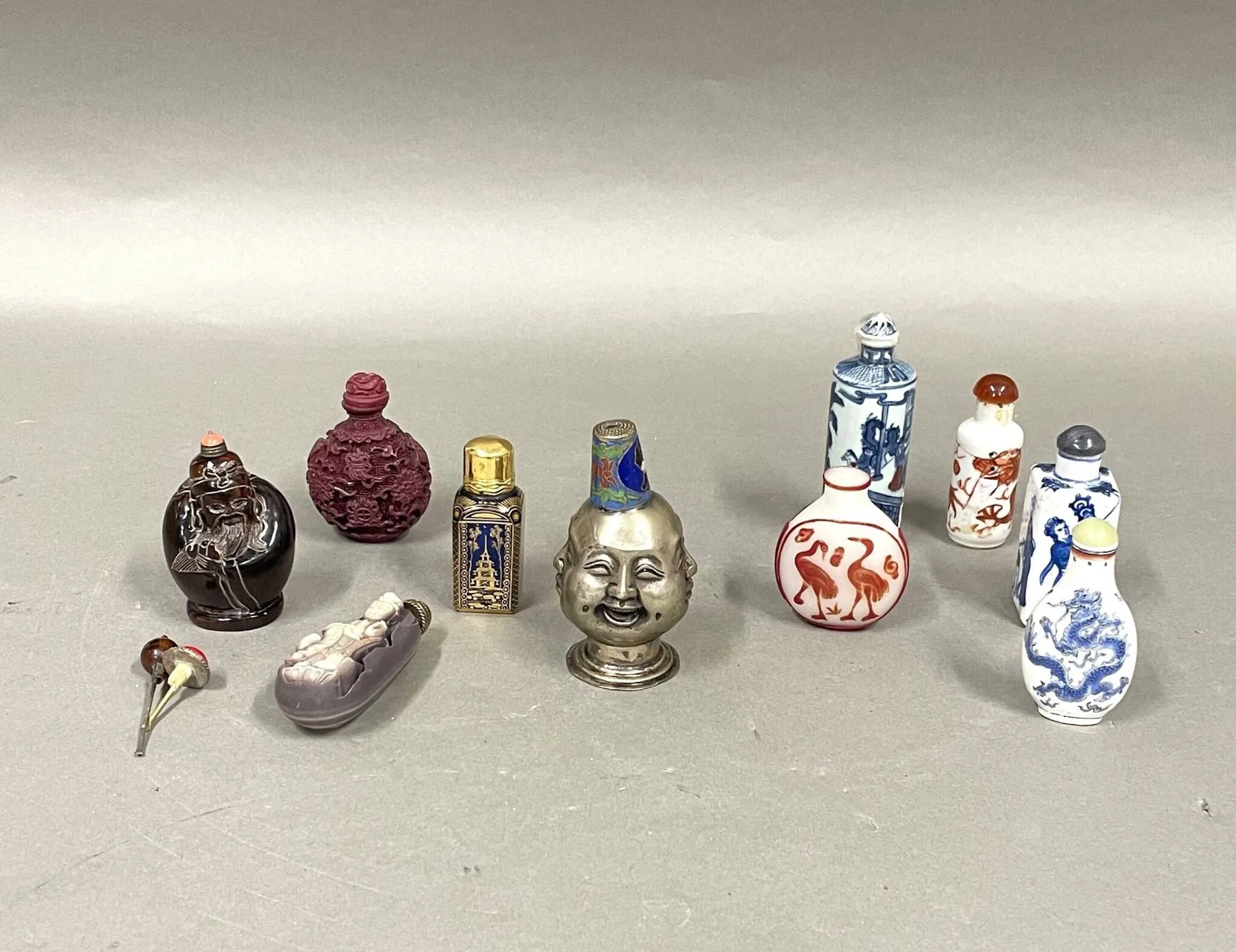 Lot de 10 tabatières en porcelaine, bois sculpté, verre au décor gravé ou métal Décor de dragons, personnages, scène de palais, pagode, animaux et trois figurant une divinité, un sage ou une tête à quatre expressions Travail chinois ou européen H : 10,5 cm (la plus haute) Petits défauts d'usage