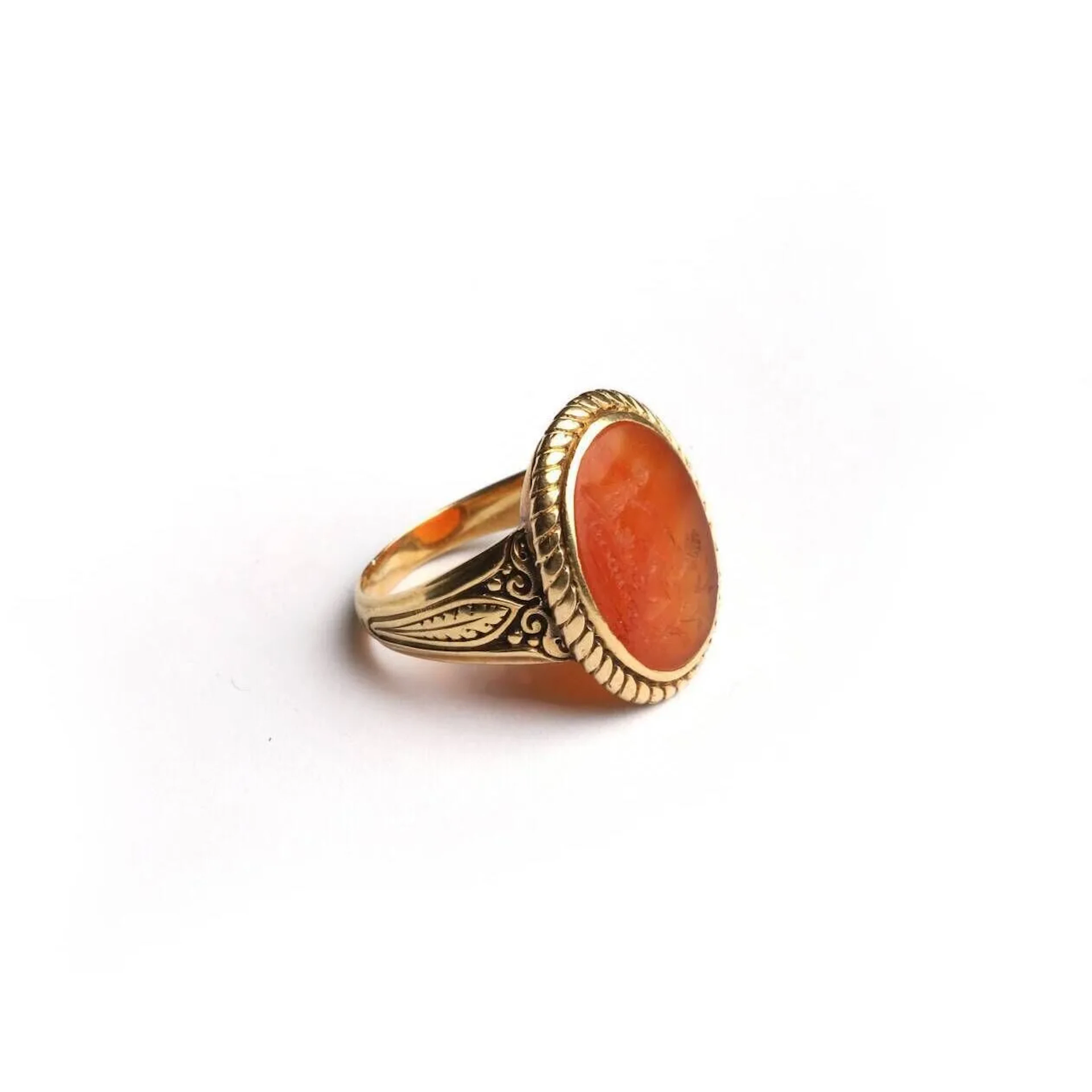 Bague en or 18k (750 millièmes) ciselé à chaton ovale incrusté d’une intaille sur cornaline figurant une femme agenouillée devant un amour assis sur un autel au coeur ardent, inscrite en bas « SOYEZ DOCILE ». L’intaille de la fin du XVIIIe siècle. La monture de la seconde moitié du XIXe siècle. TDD : 65. Poids brut : 9,9 g.