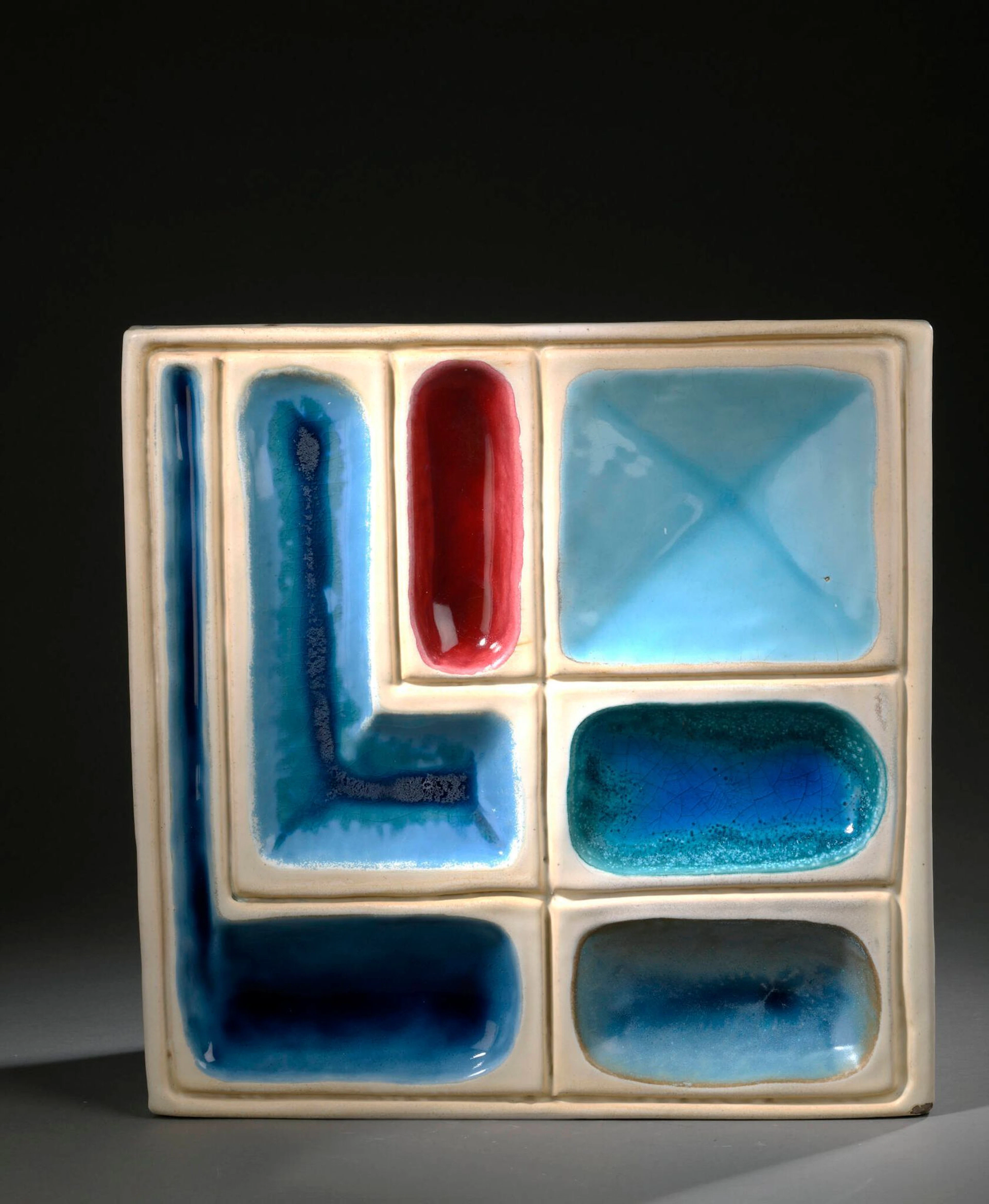 Georges JOUVE (1910-1964) Bas-relief, circa 1954 de forme carrée à décor géométrique en creux Épreuve en céramique émaillée blanc, bleu et rouge Non signé H. : 44 cm. L. : 43 P. : 4 cm. (Usures, défauts d’émaillage et légères altérations, éclats dans un angle) Bibliographie : - Georges Jouve, Edition Jousse entreprise, 2005, modèle à rapprocher reproduit p. 249.