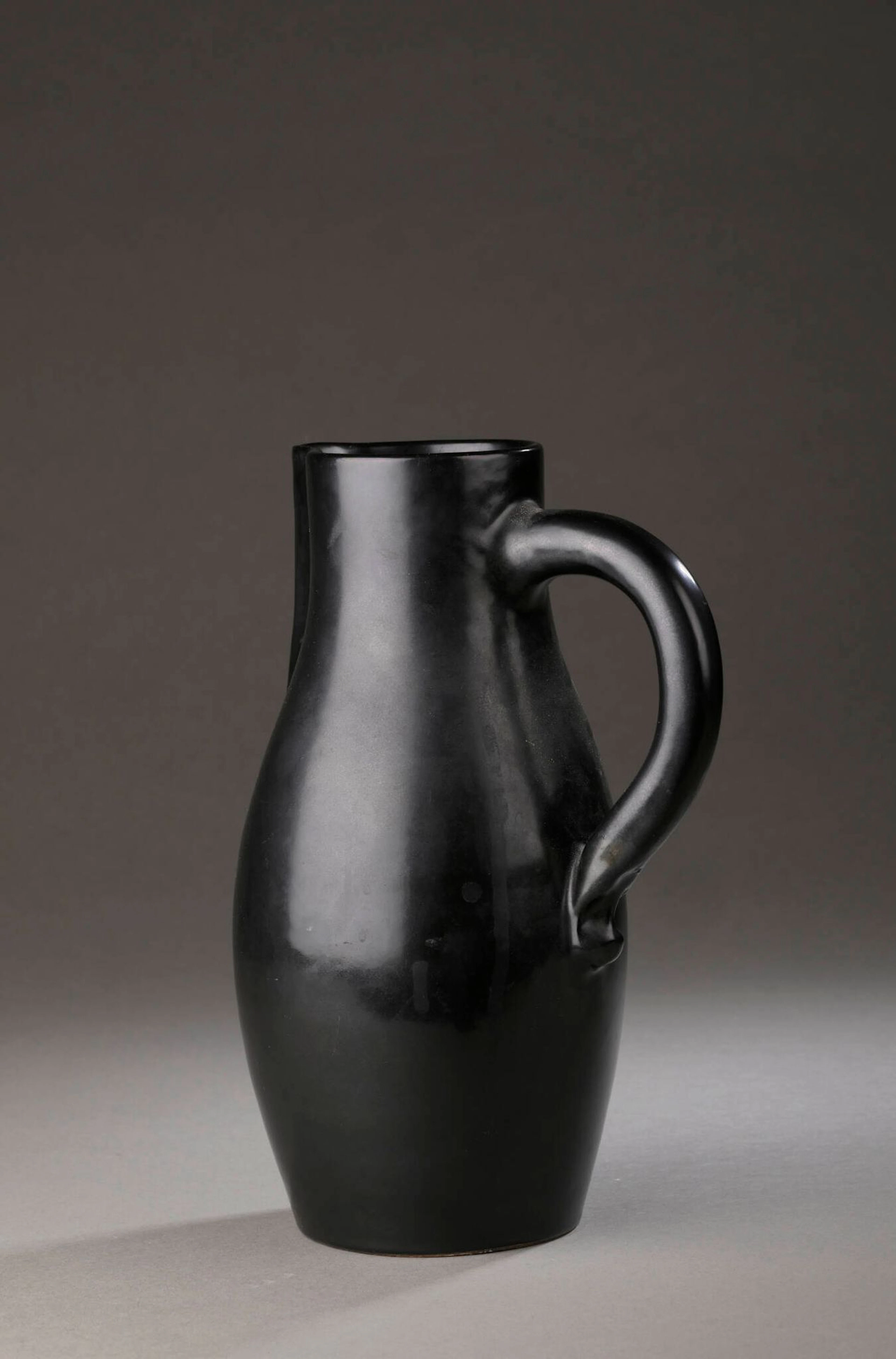 Georges JOUVE (1910-1964) Pichet, circa 1950 Épreuve en céramique émaillée noir Signé JOUVE et porte le sigle alpha de l'artiste sur l'envers. (défauts de cuisson, traces de salissure, infime éclat au col) H. : 26.3 cm. Bibliographie : - Michel Faré, Georges Jouve, Art et Industrie, 1965, modèle à rapprocher reproduit p. 70. Expert : Romain COULET