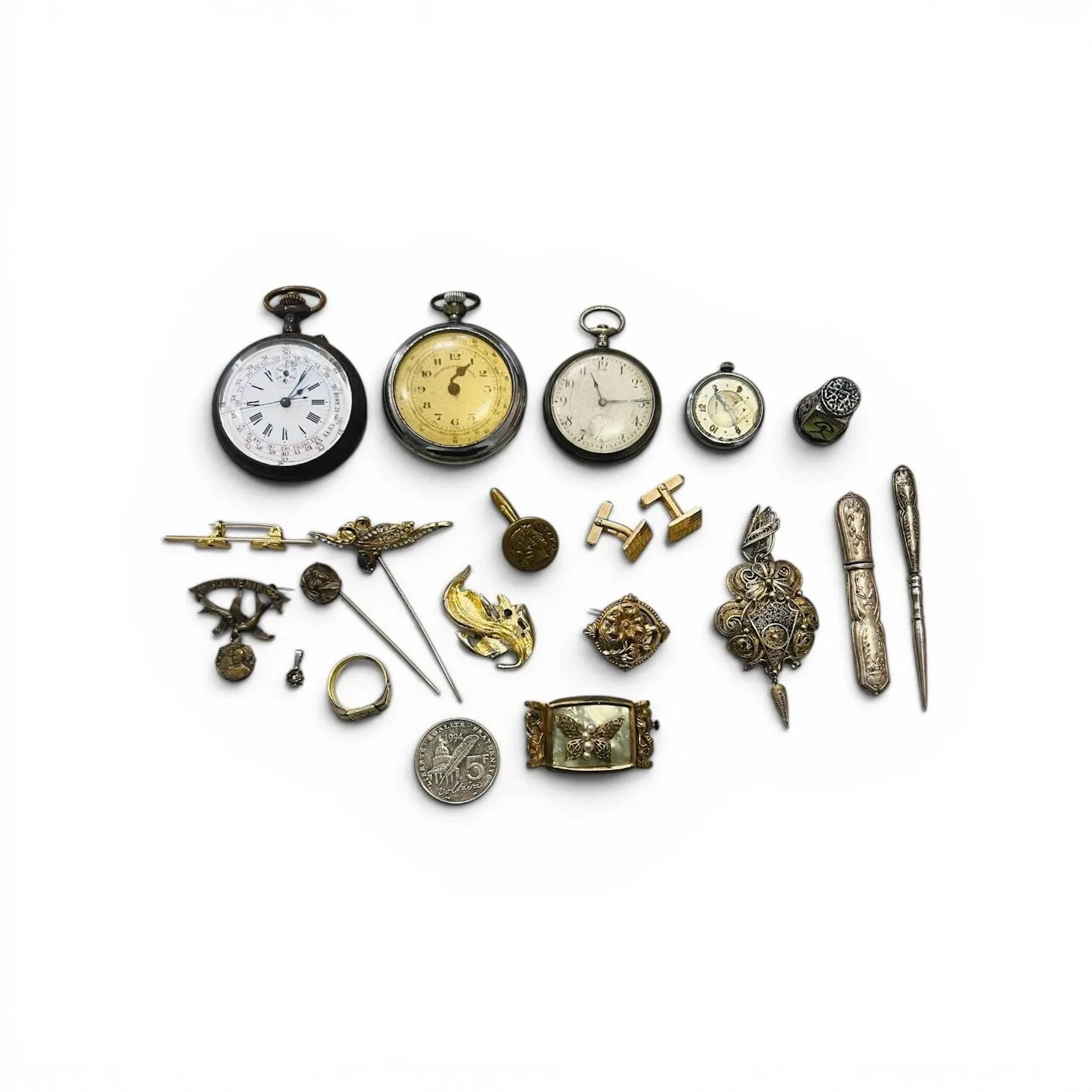 Fond de tiroir comprenant des montres de poches (dont un débris), des bijoux fantaisies en métal dont broches, boutons de manchettes, épingle de col et une chevalière. On y joint un étui à aiguilles, une alène et un dé à coudre en métal. Vendu en l'état.