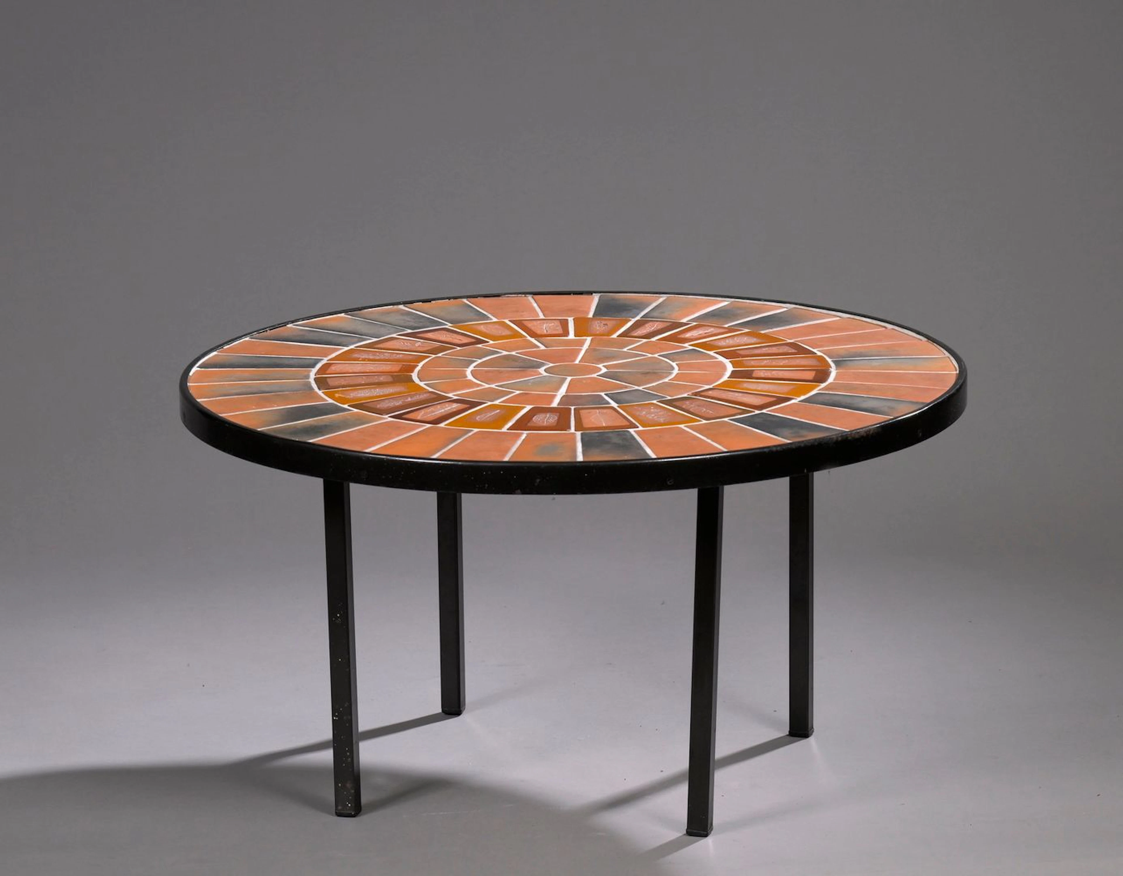 ROGER CAPRON (1922-2006) Table basse, circa 1970, à plateau circulaire composé de carreaux en grès émaillé polychrome à décor de feuilles disposé sur une structure en métal laqué de section carrée formant un piètement quadripode. Porte le cachet Capron Vallauris France. H. : 40 cm. - D. : 73 cm.