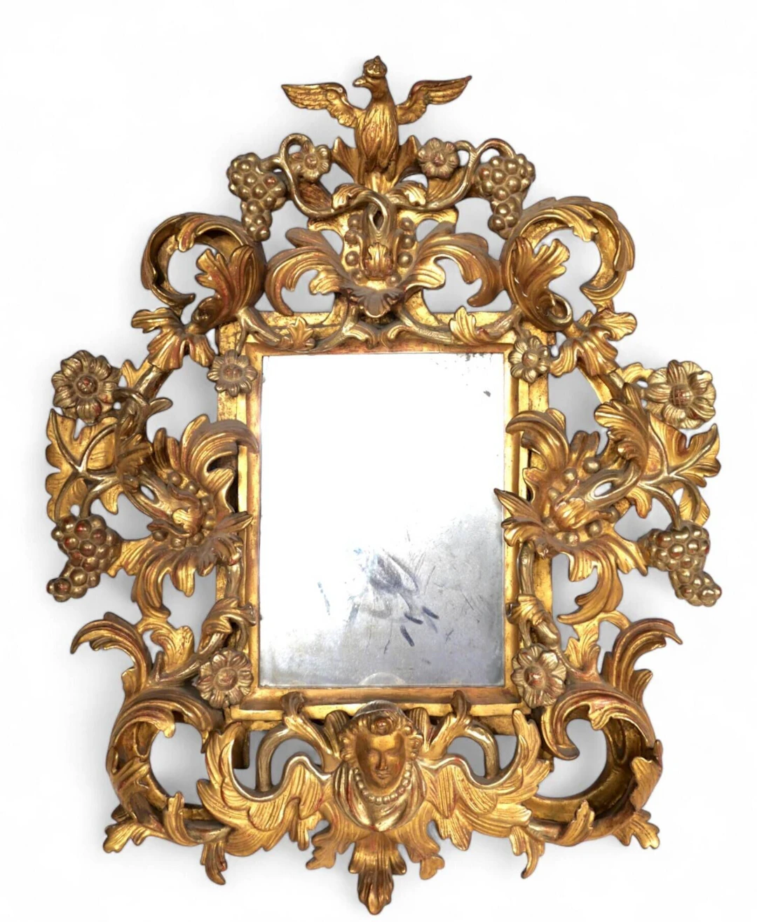 A richly carved and gilded wooden mirror featuring clusters - Lot 384