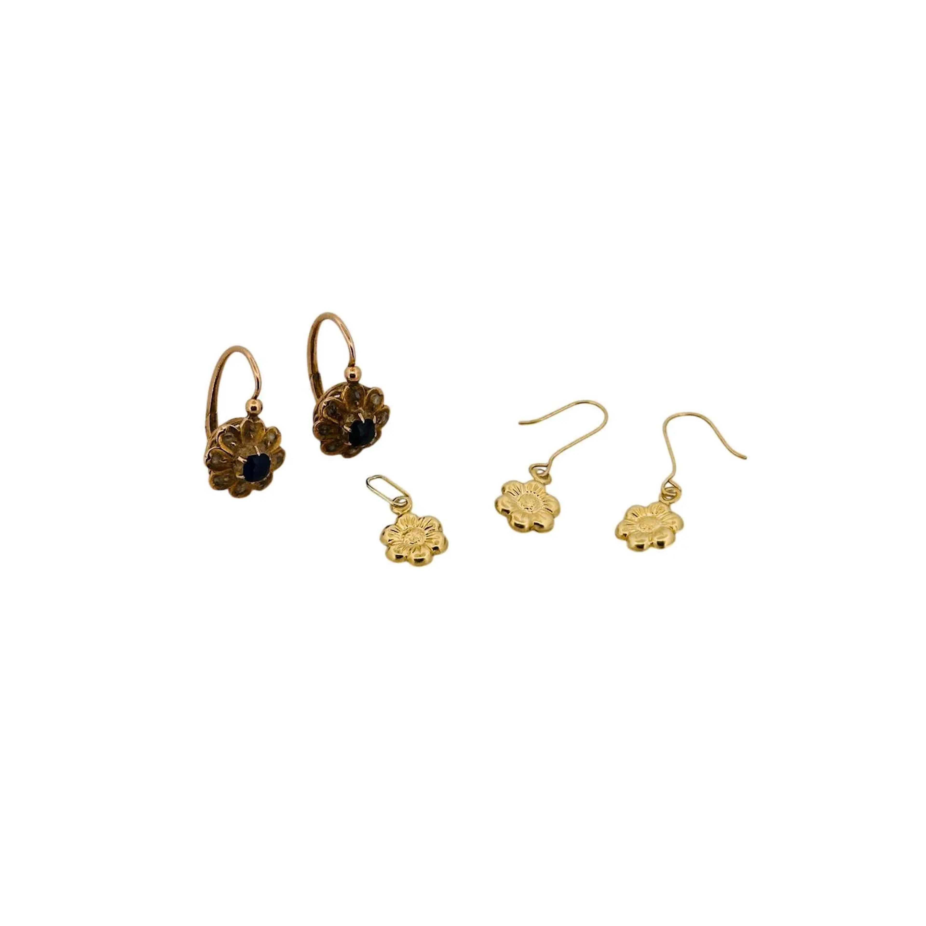 Suite de bijoux en or 18K (750) composé d'une paire de dormeuses formant des fleurettes, chacune sertie d'un saphir dans un entourage de diamants taillés en roses et d'une paires de boucles d'oreilles et un petit pendentif assorti formant des fleurs ciselées. Poids brut : 2.30 g.