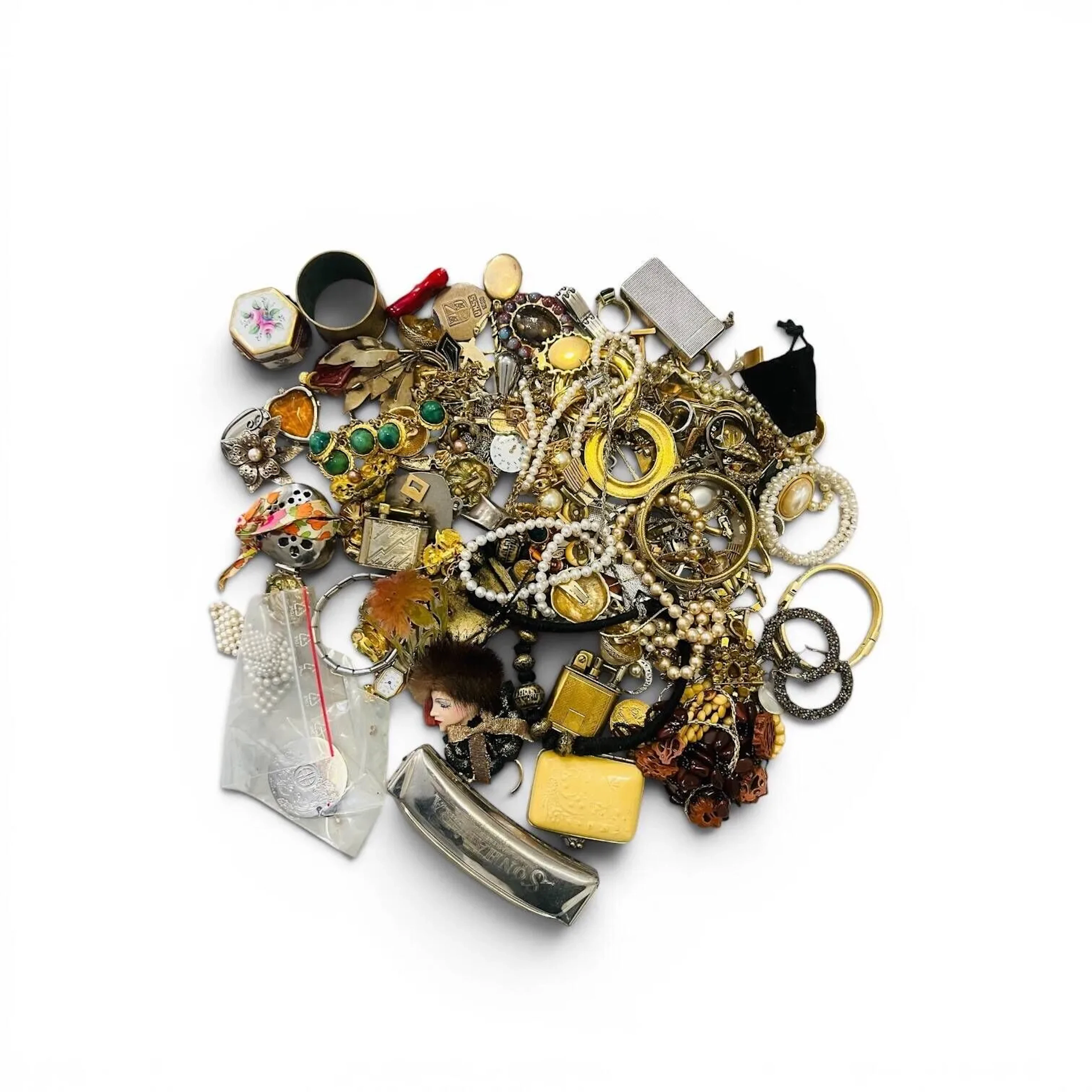Fond de tiroir composé d'un important lot de bijoux fantaisies (dont colliers, bracelets, bagues, clips d'oreilles), un médaillon en métal argenté signé Arthus Bertrand, des briquets, une suite de petites boites en matières diverses (une en porcelaine de limoges peinte à la main), un rond de serviettes en métal, un harmonica..... Vendu en l'état.