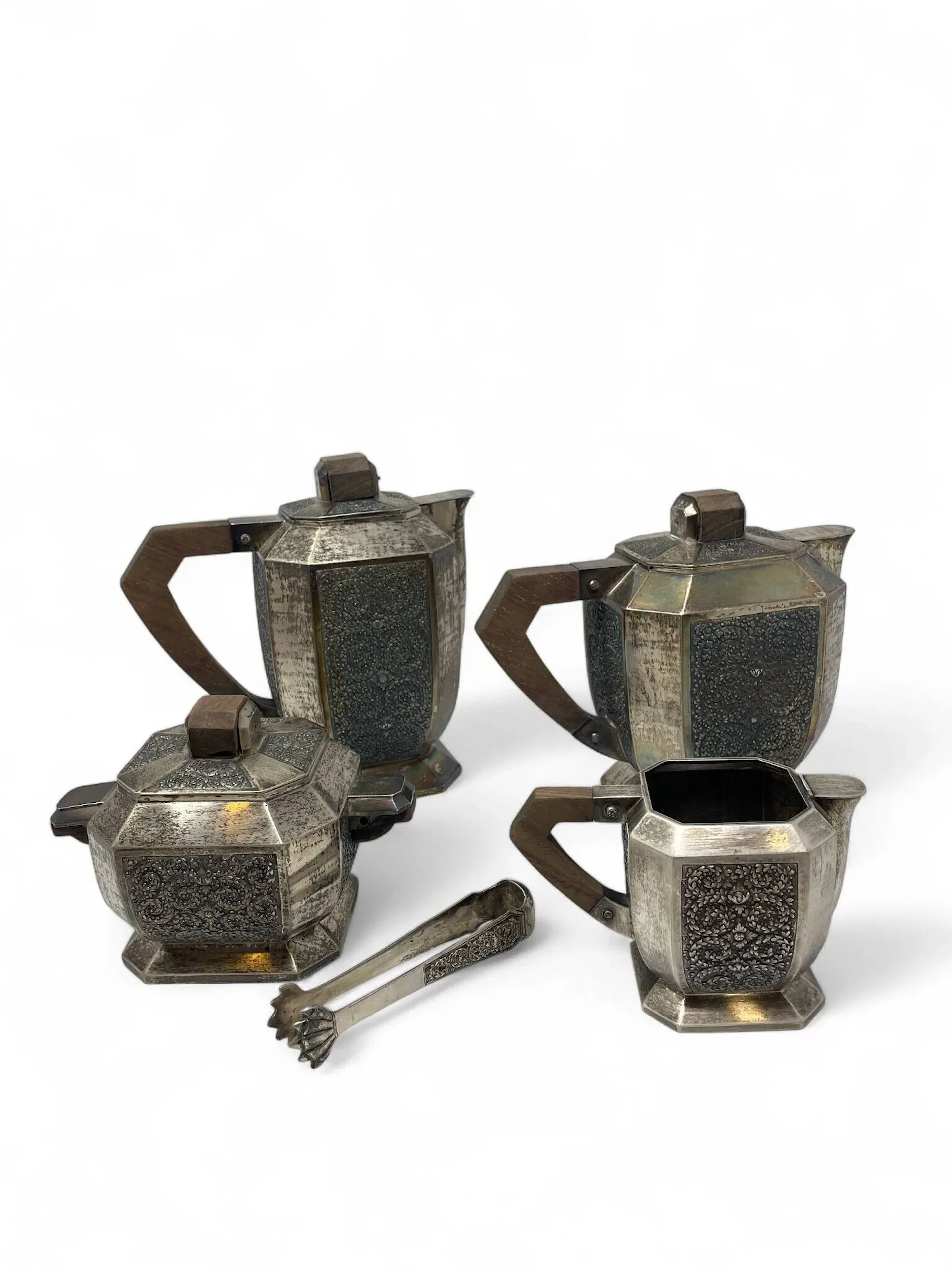 CONTRÔLE Service à thé et à café en argent (800) de section octogonale, au décor de motifs floraux sur quatre pans, prises et poignées en bois Comprenant théière, cafetière, pot à lait et sucrier avec sa pince à sucre Vietnam, XXème siècle H : 20,5 cm (cafetière) Poids brut : 3277 gr Petits enfoncements, une charnière à rattacher