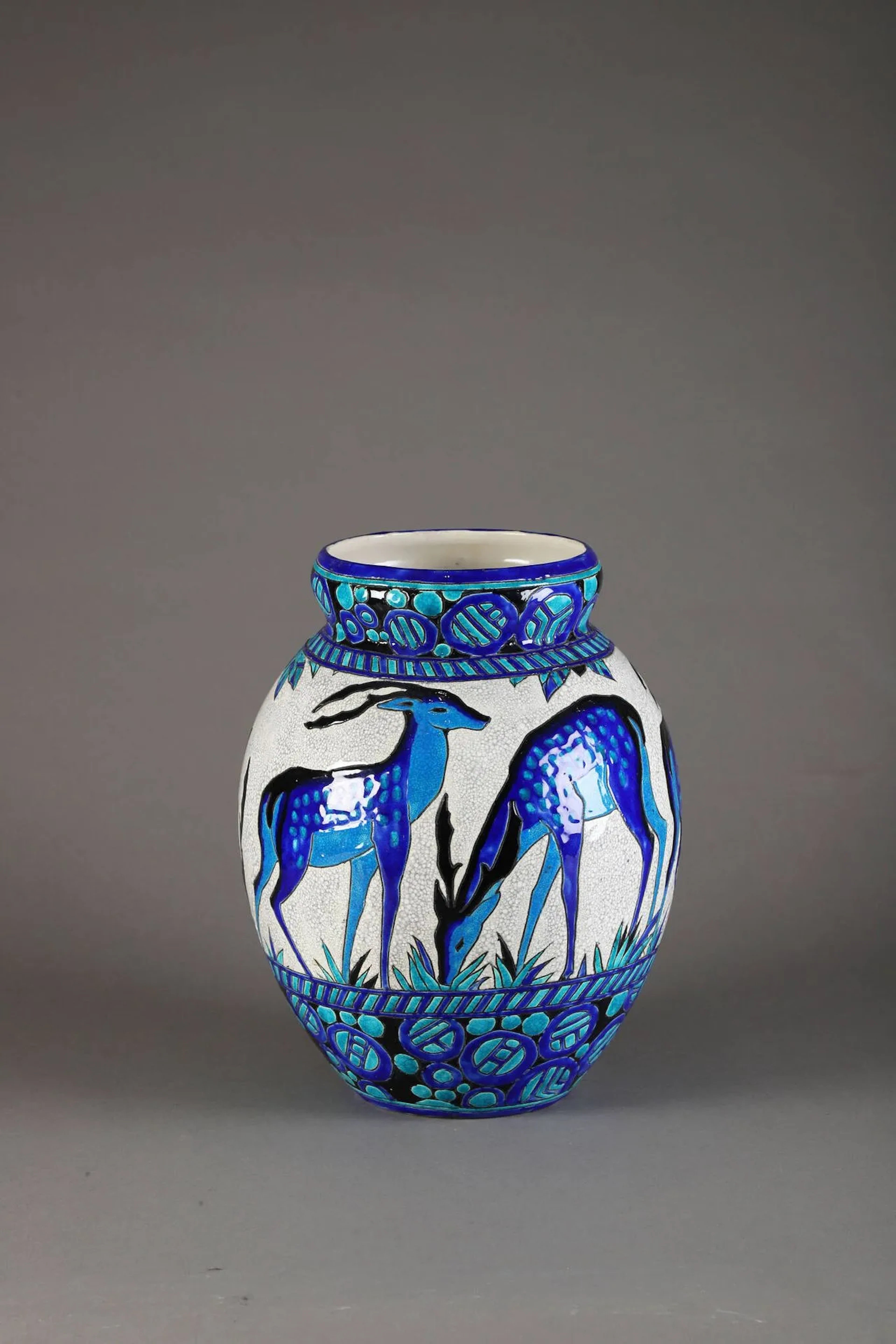 Charles CATTEAU (1880 – 1966) & BOCH FRERES KERAMIS (manufacture) – LA LOUVIERE Vase en céramique à corps ovoïde épaulé et col légèrement renflé. Décor de daims broutant sur fond de végétation stylisée. Émaux bleu, turquoise et noir sur fond blanc craquelé. Signé, cachet de la manufacture au revers et marqué D.943 (pour le décor). Haut. 34 cm Bibliographie : Marc Pairon, Art Deco Ceramics Made in Belgium, Fondation Charles Catteau, 2006, décor n°943 référencé p. 659 et modèles au décor similaire reproduits p. 274.