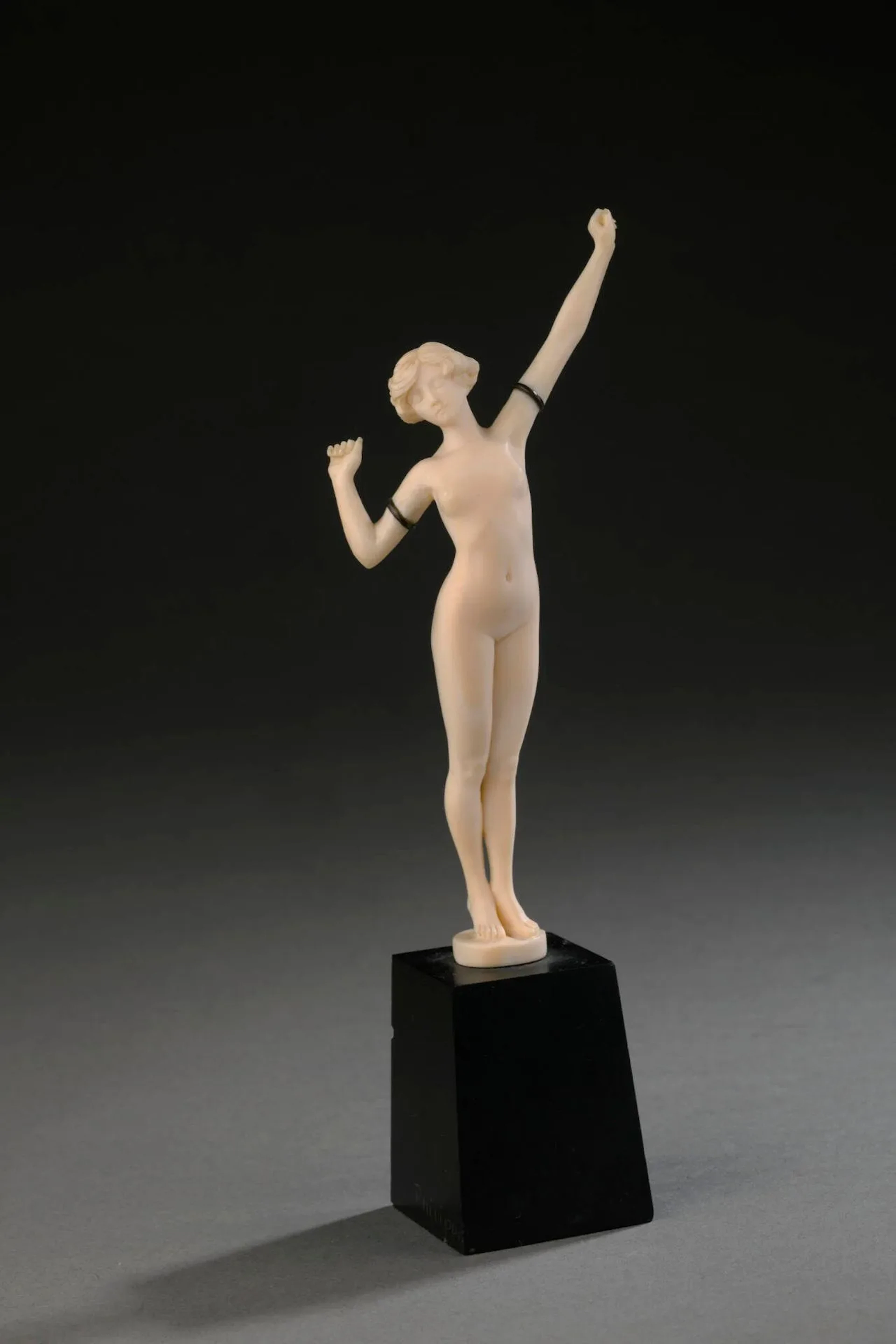 Paul PHILIPPE (attribué à) « Réveil ». Sculpture en ivoire et bracelets de bras en métal. Taille directe. Socle conique en pierre noire (petits éclats). Signature apocryphe sur le socle. Haut. 18 cm (totale) Accompagné de son CIC n°FR26033000046-K