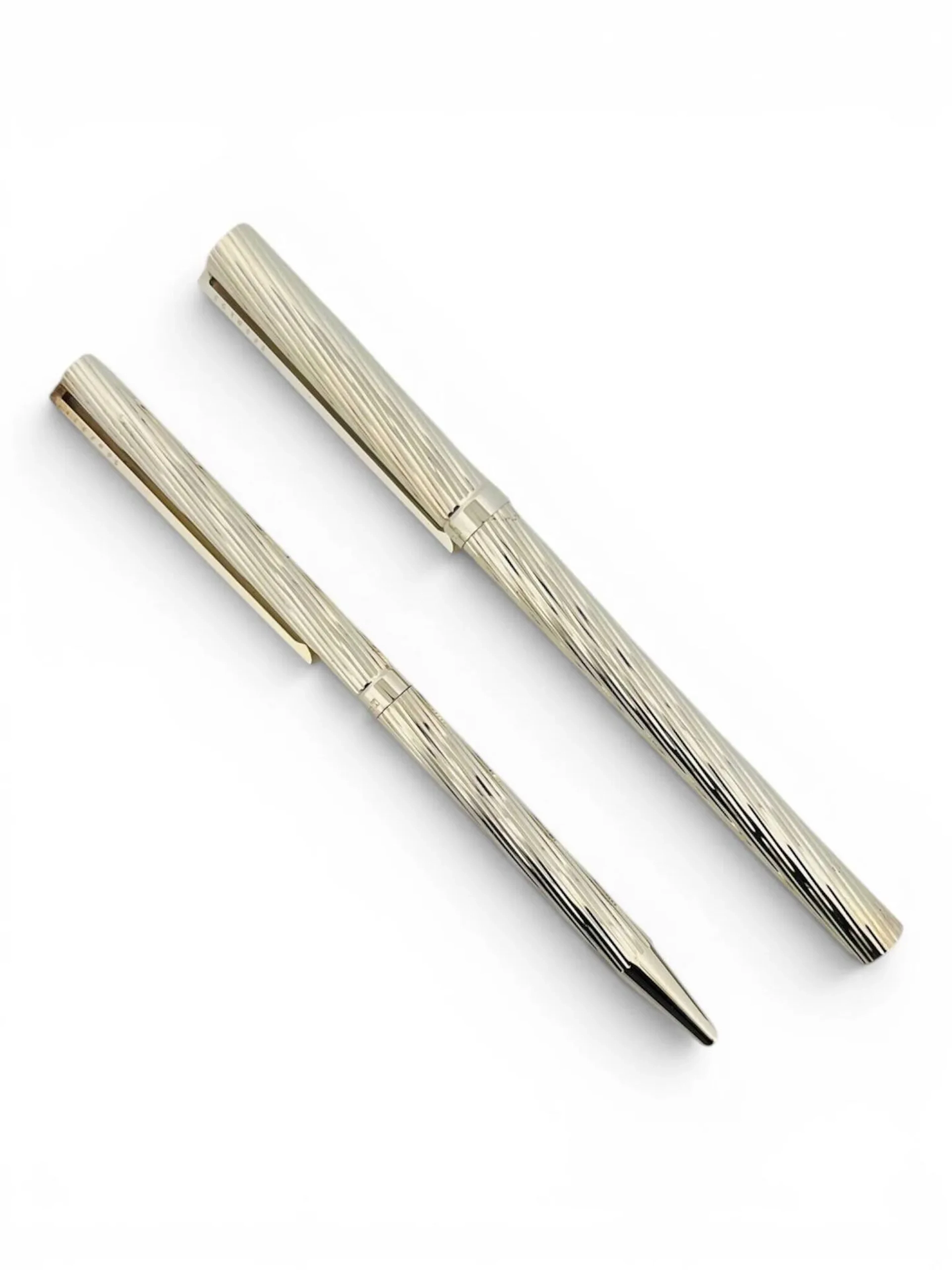 ST Dupont Parure comprenant un stylo plume et un stylo bille en métal argenté à décor de motifs torses, plume en or jaune (750). Signés et numérotés 56HFT31 et 57GHL95 Dans un écrin signé, avec certificats et piston de recharge