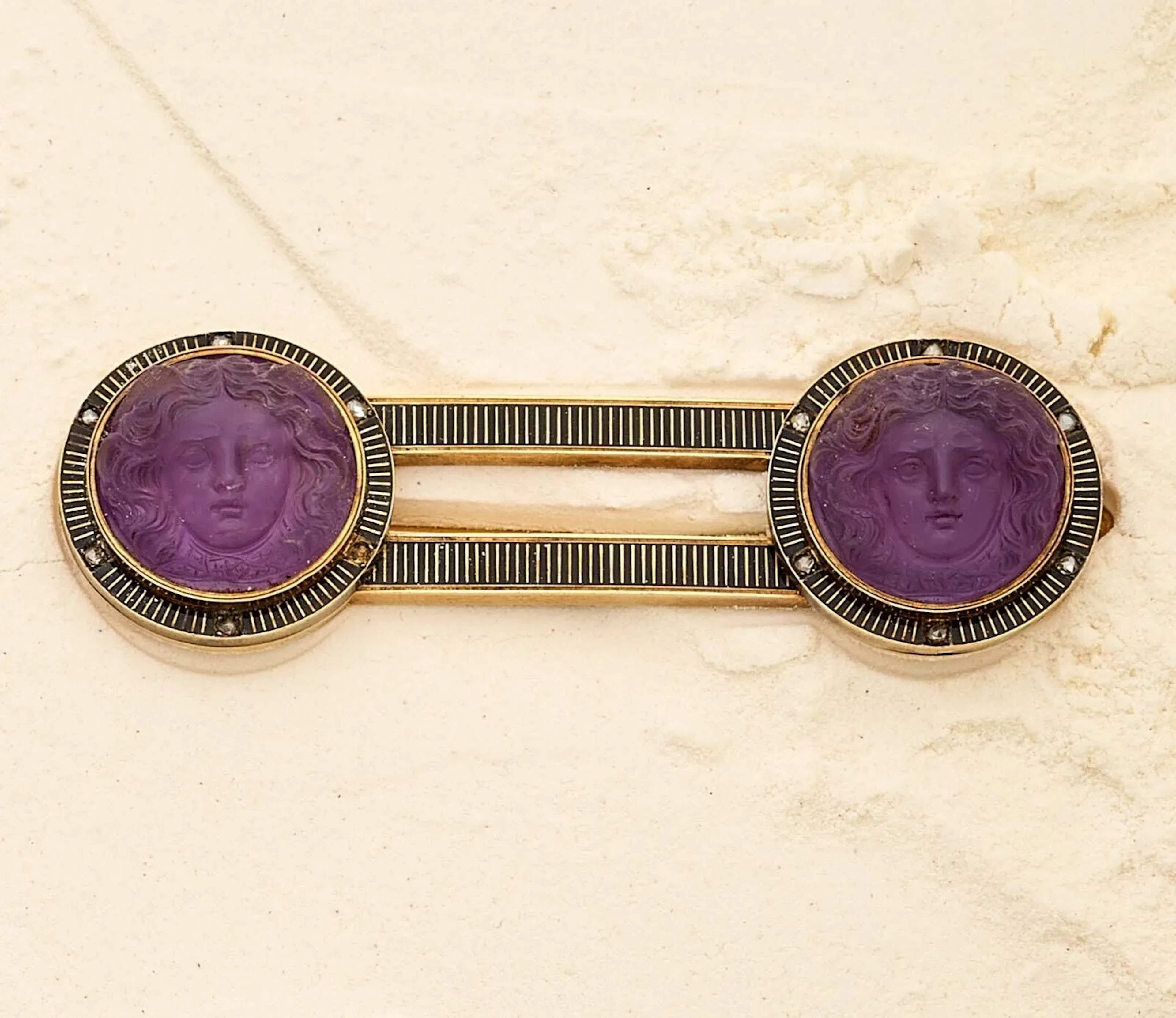 Broche barrette en or 18k (750e), les extrémités ornées de 2 améthystes gravées figurant Hermès, dans un entourage de rayures en émail noir ponctué de petites roses diamantées. Travail français d'époque Napoléon III. Poids brut : 22.20 g. Dimensions : 7 x 2.3 cm.
