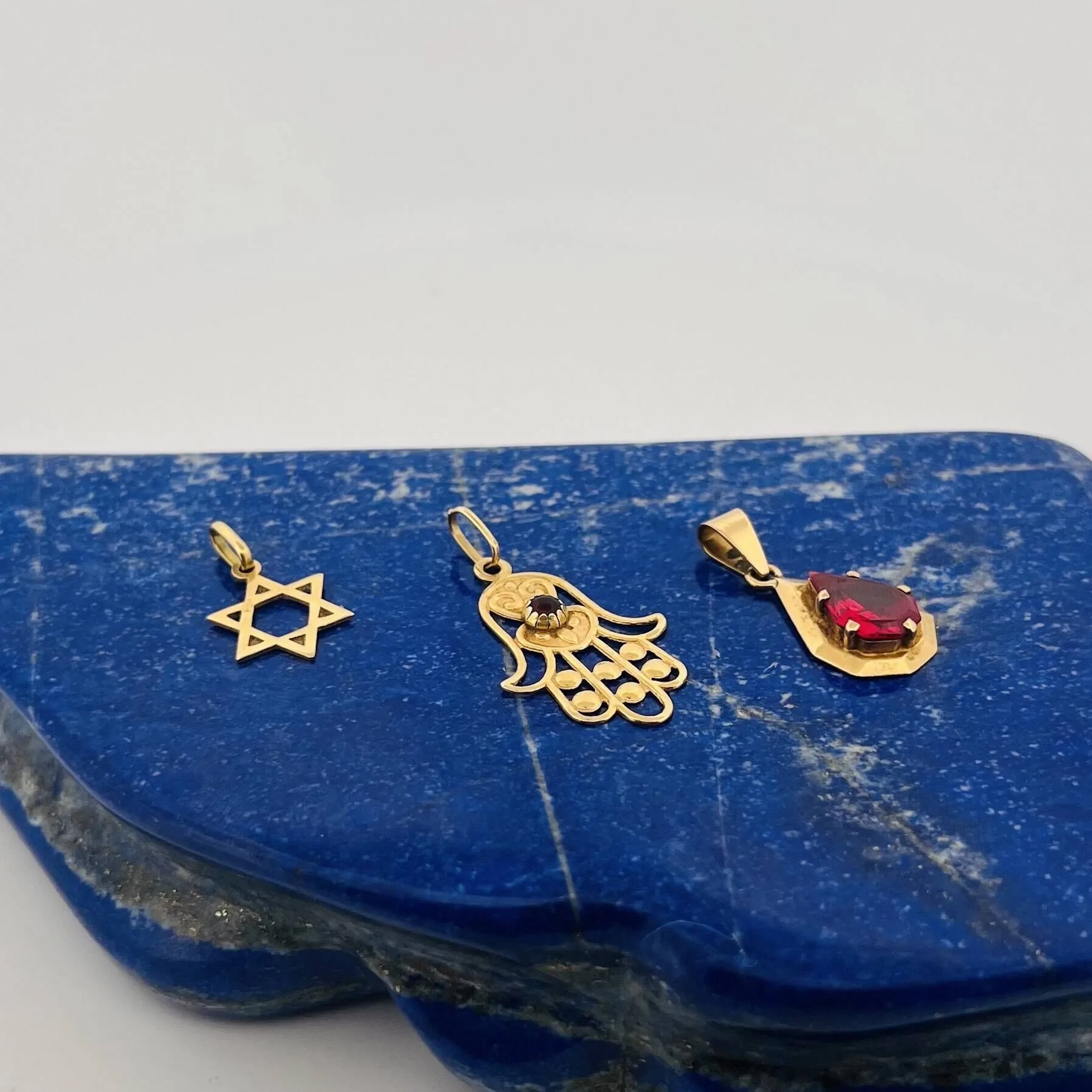 Three yellow gold (750) pendants featuring a Star of David, - Lot 64