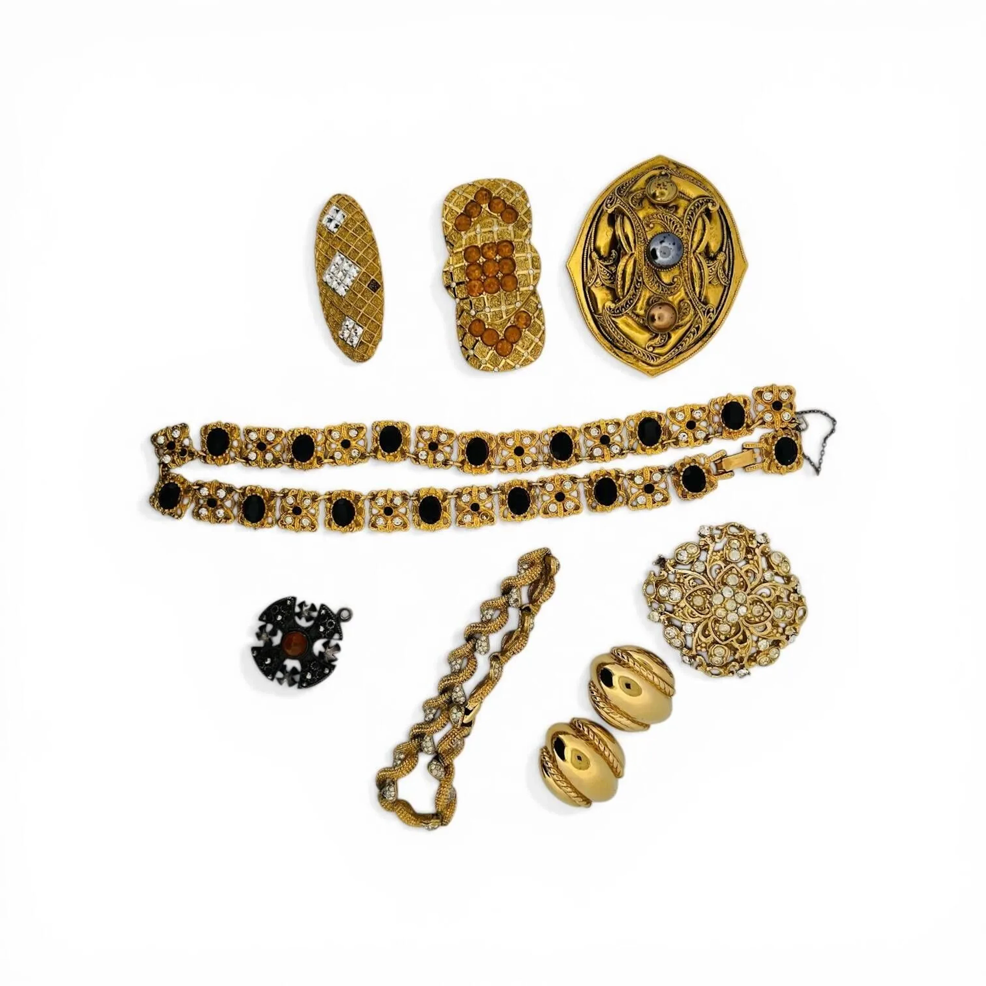 Lots bijoux fantaisie comprenant: - Christian DIOR Paire de clips d'oreilles en métal doré à décor de godrons et motifs de cordages. Signés sur le dessous 'Chr.Dior Germany" Années 1980 Diam. 25 mm - BALENCIAGA Broche de forme ovale en métal doré à décor de croisillons à fond amati et serti de strass formant des motifs losangiques Signé sur le dessous 21 x 50 mm Salissures - BALENCIAGA Broche de forme ovale en métal doré à décor de croisillons à fond amati et serti de strass formant des motifs losangiques Signé sur le dessous 21 x 50 mm Salissures - BALENCIAGA Broche en métal doré stylisant un nœud à décor de quadrillages à fond amati sommés de strass translucides et agrémentés de strass oranges formant motifs géométriques. Signé sur le dessous 31 x 60 mm Manques des strass - SALEM Pendentif en argent sterling (835) stylisant une croix grecque centrée d'un cabochon orange (calcédoine ?) et cantonnée de croix. Poids brut: 6,4 gr - SPHINX Collier articulé en métal doré à maillons ajourés centrés de strass. Chaîne de sécurité. Signé au dos Long. 47,5 cm Manques de strass On y joint un bracelet et deux broches fantaisie