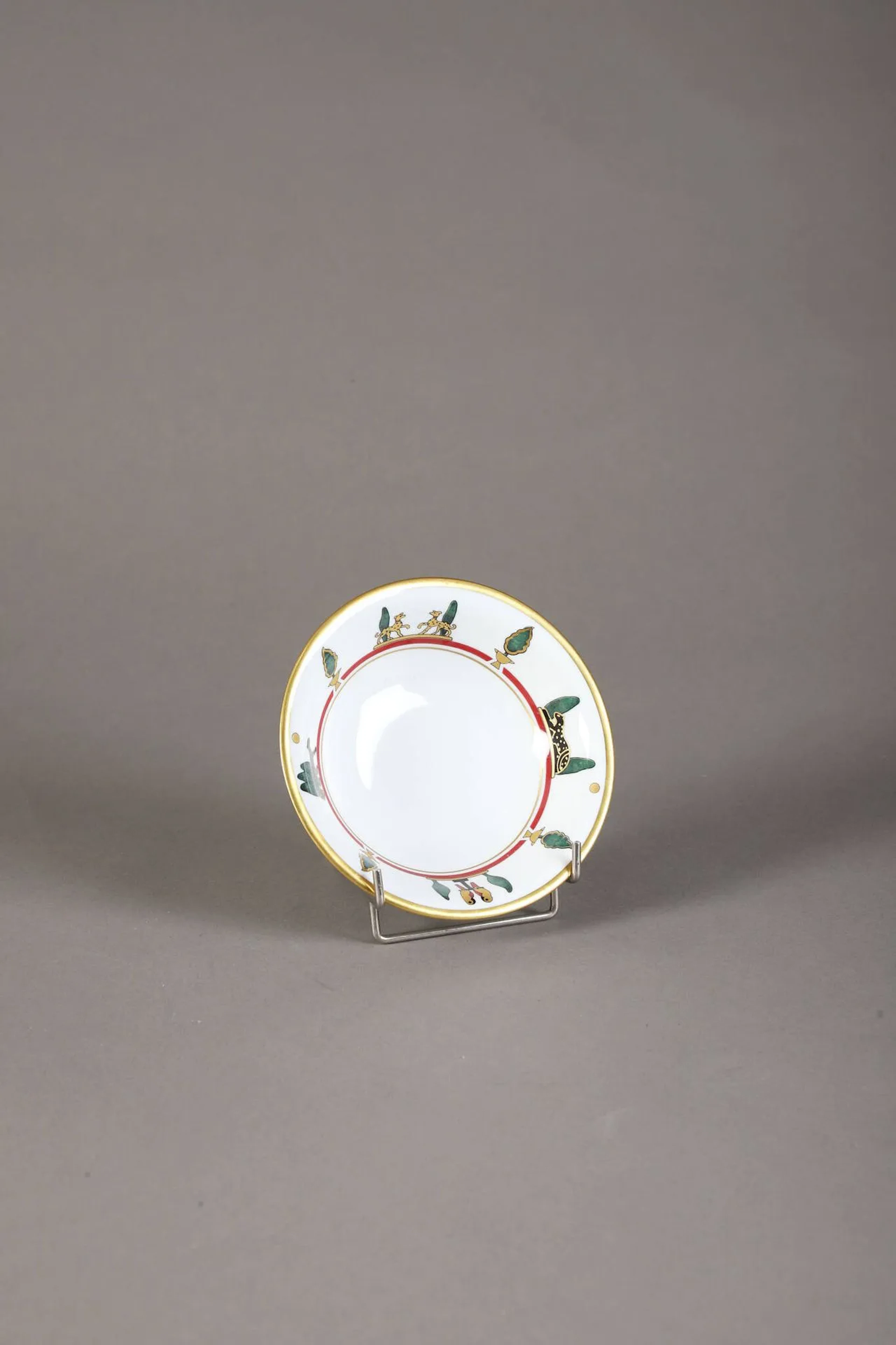 LIMOGES pour CARTIER Assiette à bouillie modèle "LA MAISON DE CARTIER " en porcelaine à décor émaillé de panthères, volatiles et paysage arboré, filet doré sur le pourtour. Marques sur le dessous et numéro 49 à l'or H. 4,5 - Diam. 16 cm Dans sa boite d'origine
