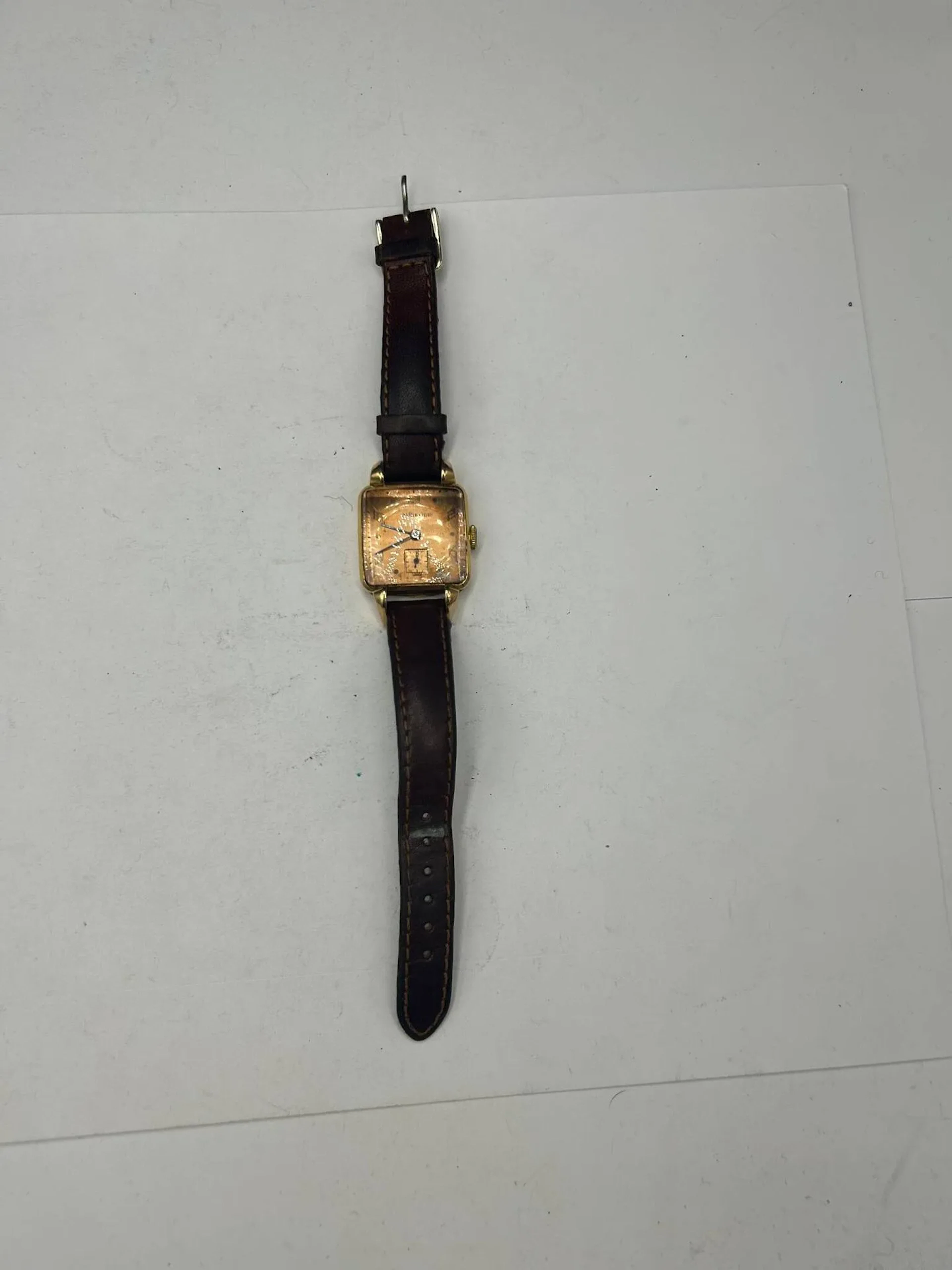 AURECOLE Montre bracelet d'homme, boitier carré en or jaune 18K (750), cadran cuivre, index chiffres arabes et point formant les heures, mouvement mécanique, bracelet en cuir marron à boucle ardillon. Poids brut : 31.38 g.