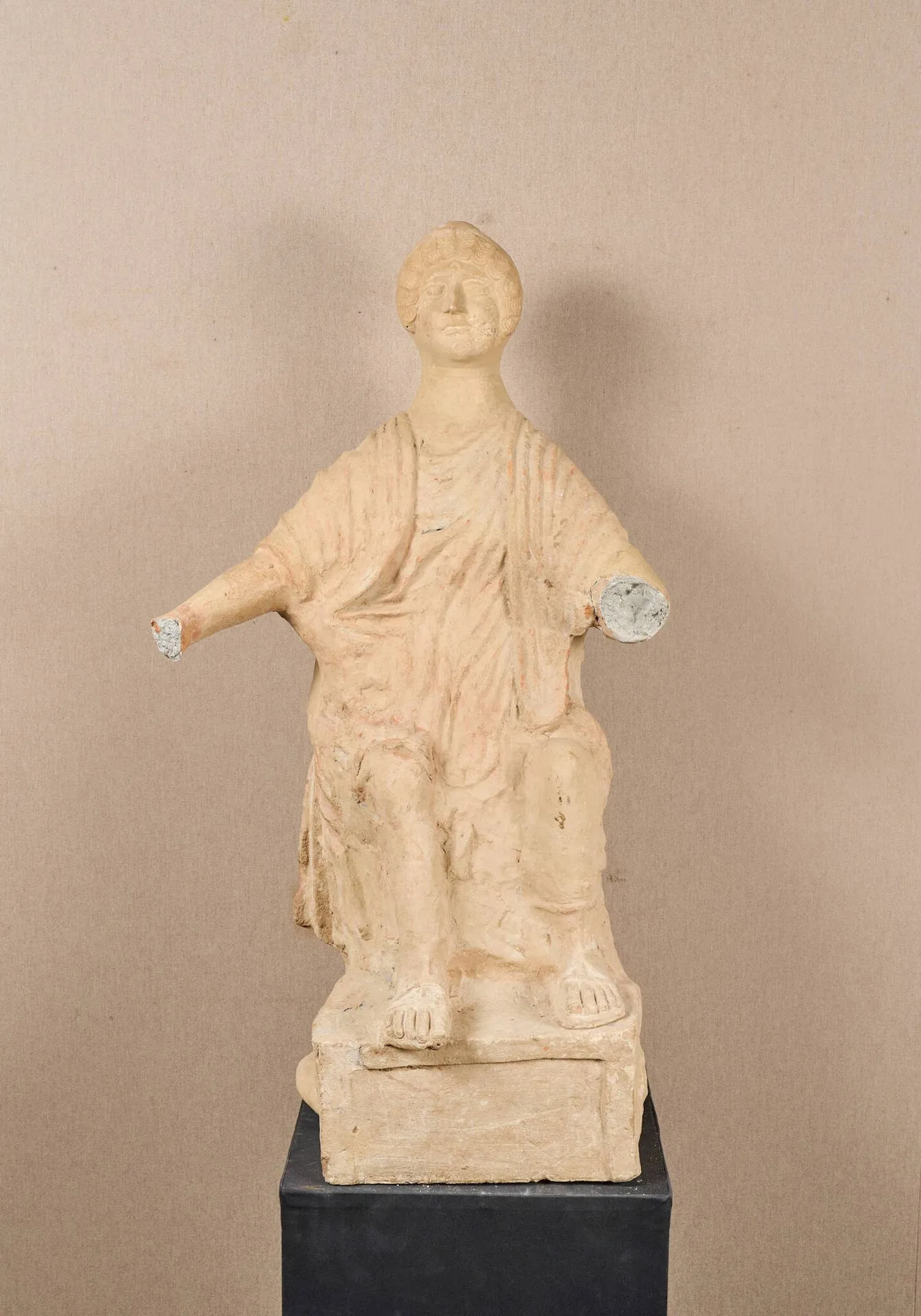 Grande statue figurant un personnage féminin drapé, vêtu d’un chiton, assis, les pieds reposant sur une terrasse. Le personnage porte des sandales. Elle tient une patère dans sa main droite. Probablement la déesse Junon. Terre cuite. Nombreux bouchages, principalement de surface. Cassée et recollée. Art romain, Ier siècle av. J.-C. H. : 94 cm Provenance : ancienne collection Grenier