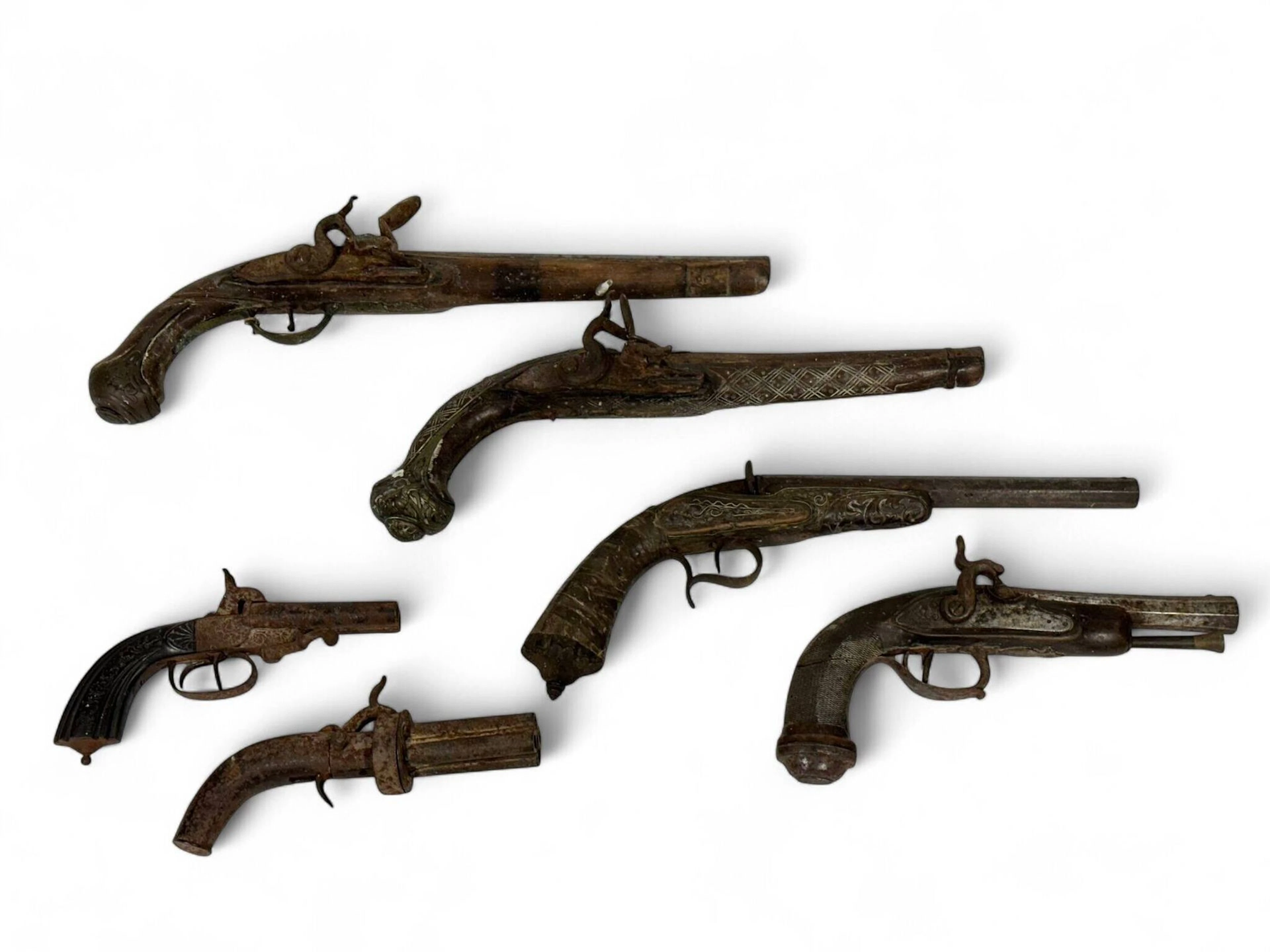 Ensemble de six armes. Comprenant : -Pistolet à broches. Double canon en table. Coffre ciselé et crosse en ébène cannelée. Bonne mécanique. Oxydations. Longueur totale :18 cm. Époque vers 1870. -Petit revolver à poivrière. Quatre canons rotatifs et système à percussion. Mauvais état. -Pistolet de tir de salon système Flobert. Un coup à chargement par la culasse. Canon octogonal et crosse en noyer sculpté. Elle est enrichie de fils de laiton et d’une réparation en peau de chèvre après un passage en orient. Bonne mécanique. Longueur totale : 34 cm. Époque vers 1870. -Pistolet d’officier en demi-arçon. Platine à silex transformée à percussion. Canon octogonal, tromblonné et rayé cheveux. Crosse en noyer quadrillé et garnitures fer. Accident mécanique et fente au bois. Travail vers 1800. -deux pistolets à silex pour l’orient. Incomplets, mauvais états. Lot vendu en l’état. Armes de catégorie D.
