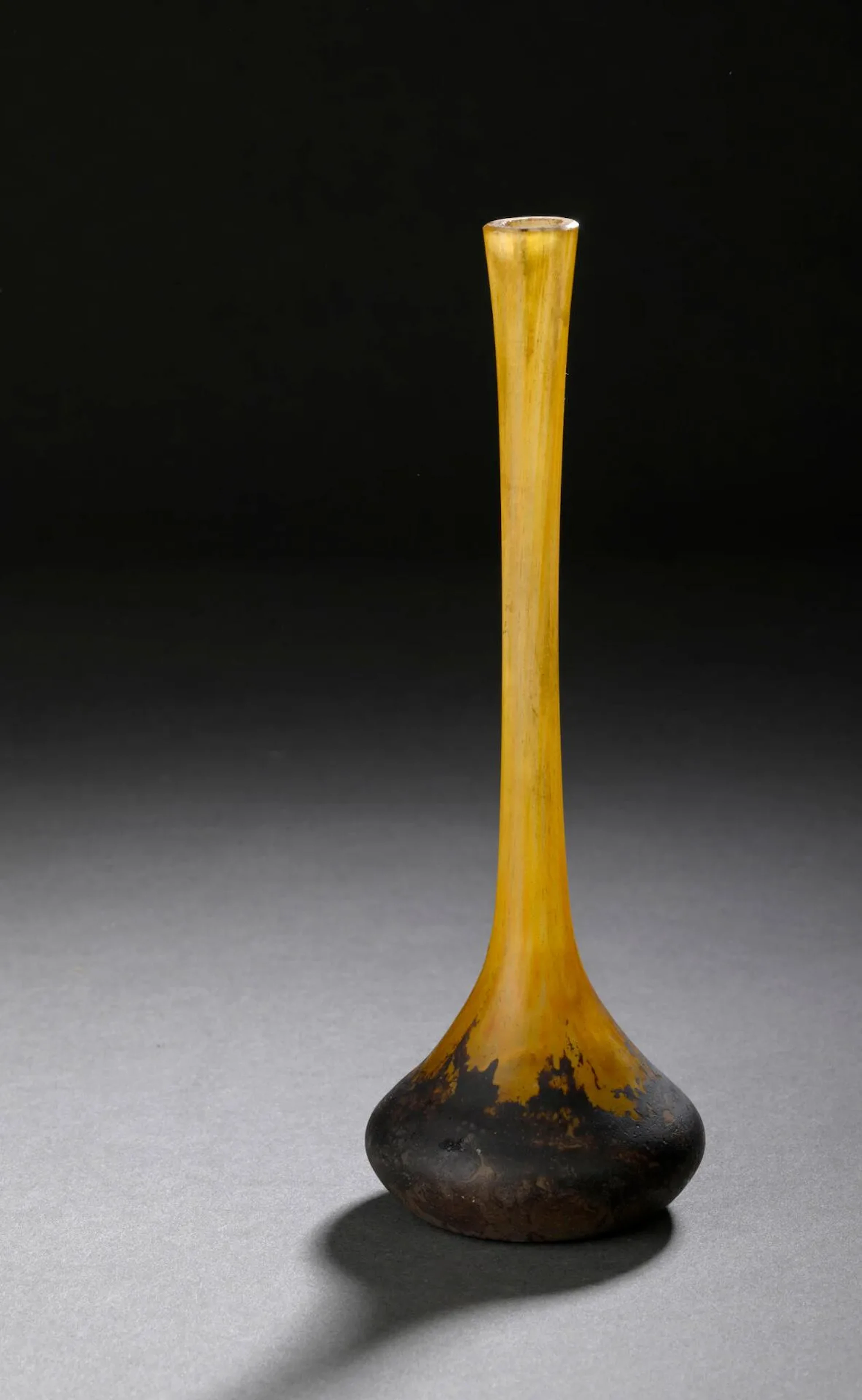 DAUM – NANCY Berluze à long col conique sur base renflée. Épreuve en verre poudré marmoréen brun violacé sur fond jaune orangé (infimes égrenures au col). Signée. Haut. 16 cm