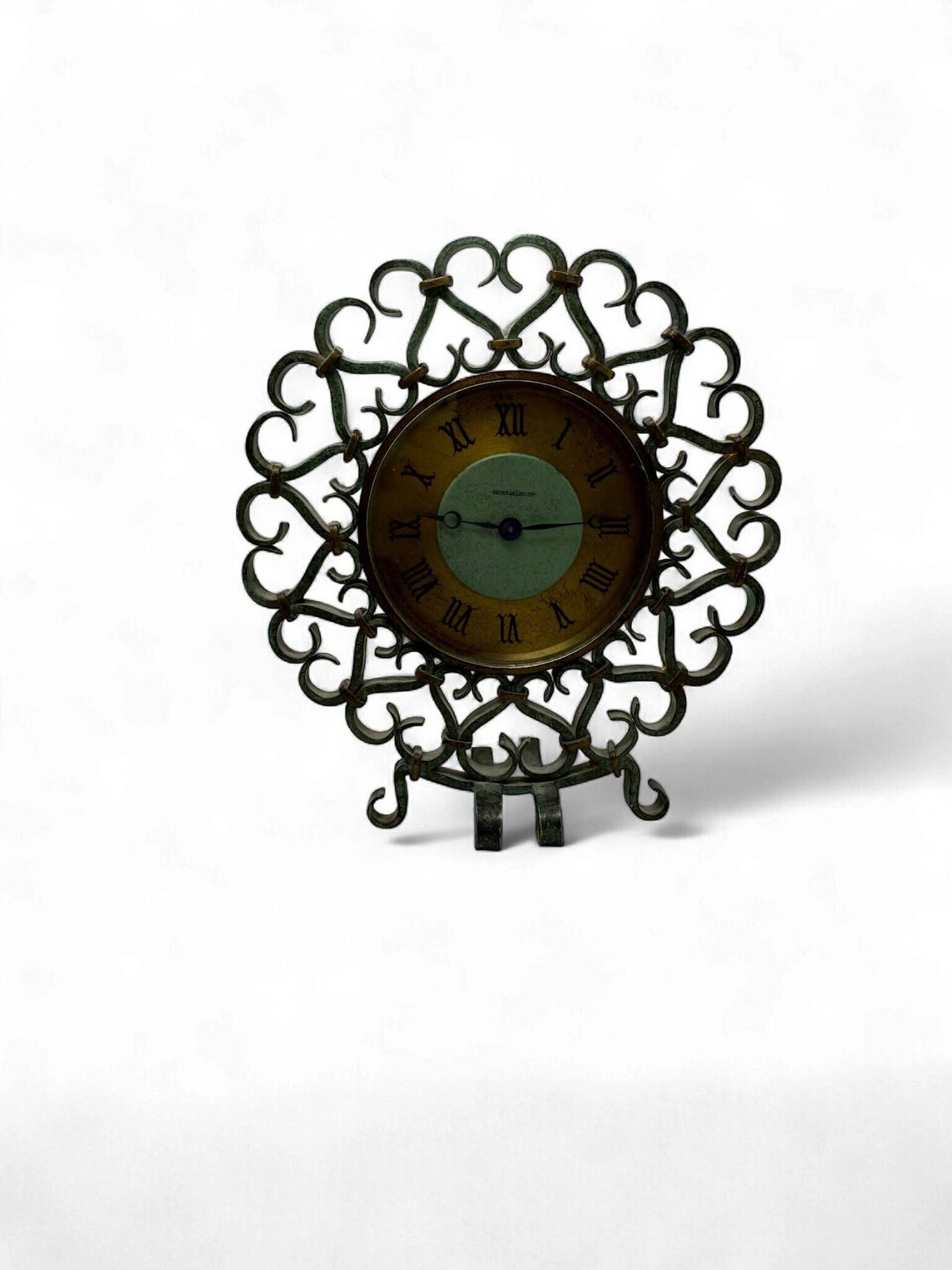 JAEGER LECOULTRE & Gilbert POILLERAT (attribué à) Pendulette de bureau à cadran circulaire et chiffres romains émaillés noir sur fond doré dans un entourage en fer forgé à décor d’entrelacs patinés vert antique reliés par des ruban de fer doré. Signé sur le cadran. Haut. 23 cm