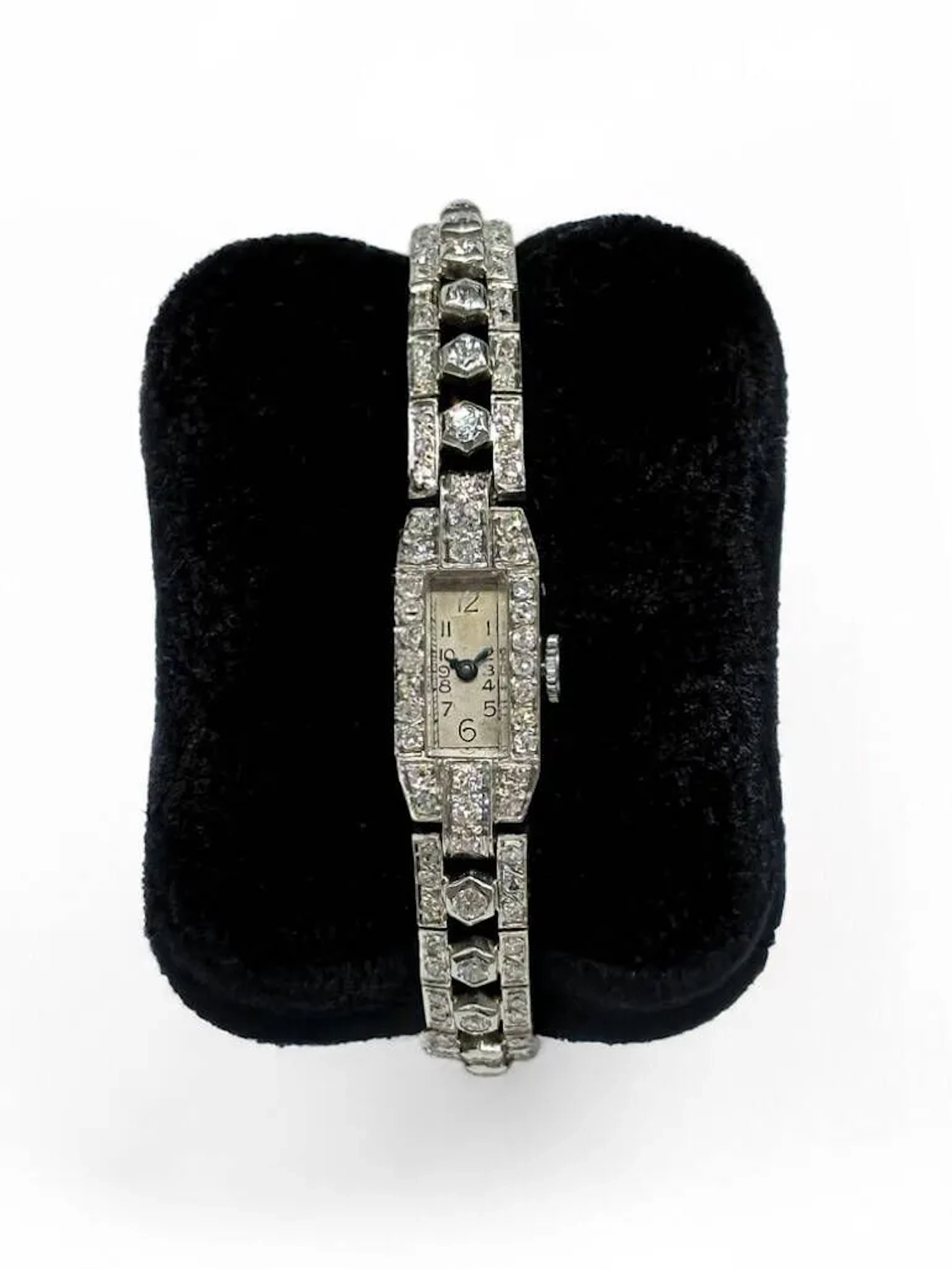 Montre de dame en platine (950) et 28 diamants en chute (0,07 cts env. pour les plus gros) sur le bracelet flanqués de mini brillants. Fermoir à clip en or blanc (750) surmonté d'une petite pierre et chainette de sureté Cadran rectangulaire à chiffres arabes sur fond champagne, aiguilles bleuies Boitier : 22 x 11 mm L : 16,5 cm Poids brut : 28,9 grammes