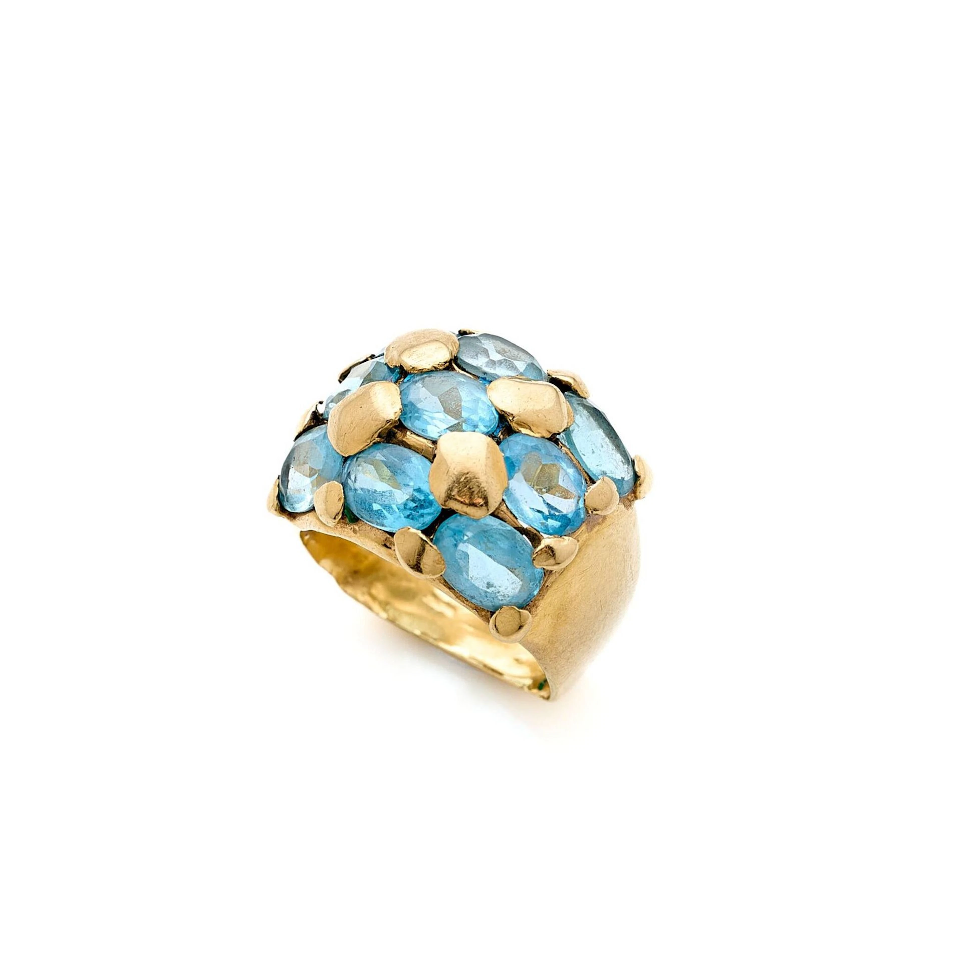 Bague en or 18k (750e), pavée de topazes bleues ovales facettées alternés de gros grain. (anneau déformé, pierres accidentées) Poids brut: 10.50 g. Tour de doigt: 54.