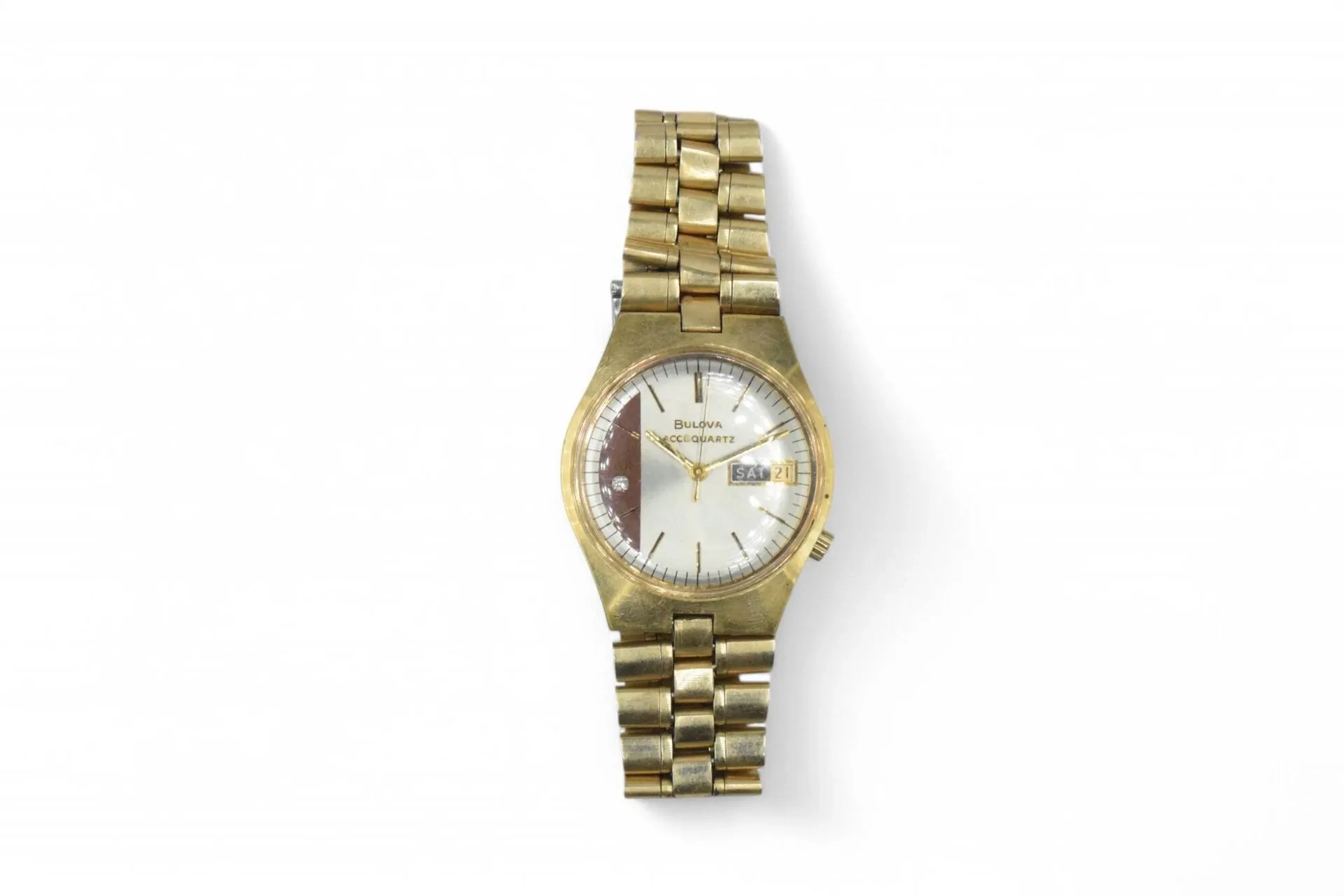 BULOVA ACCUQUARTZ Montre bracelet pour homme en métal doré, cadran gris et rouge, index bâtons formant les heures, date par guichet à 3h, mouvement quartz, bracelet intégré en métal à boucle déployante signée. Diam. : 36 mm