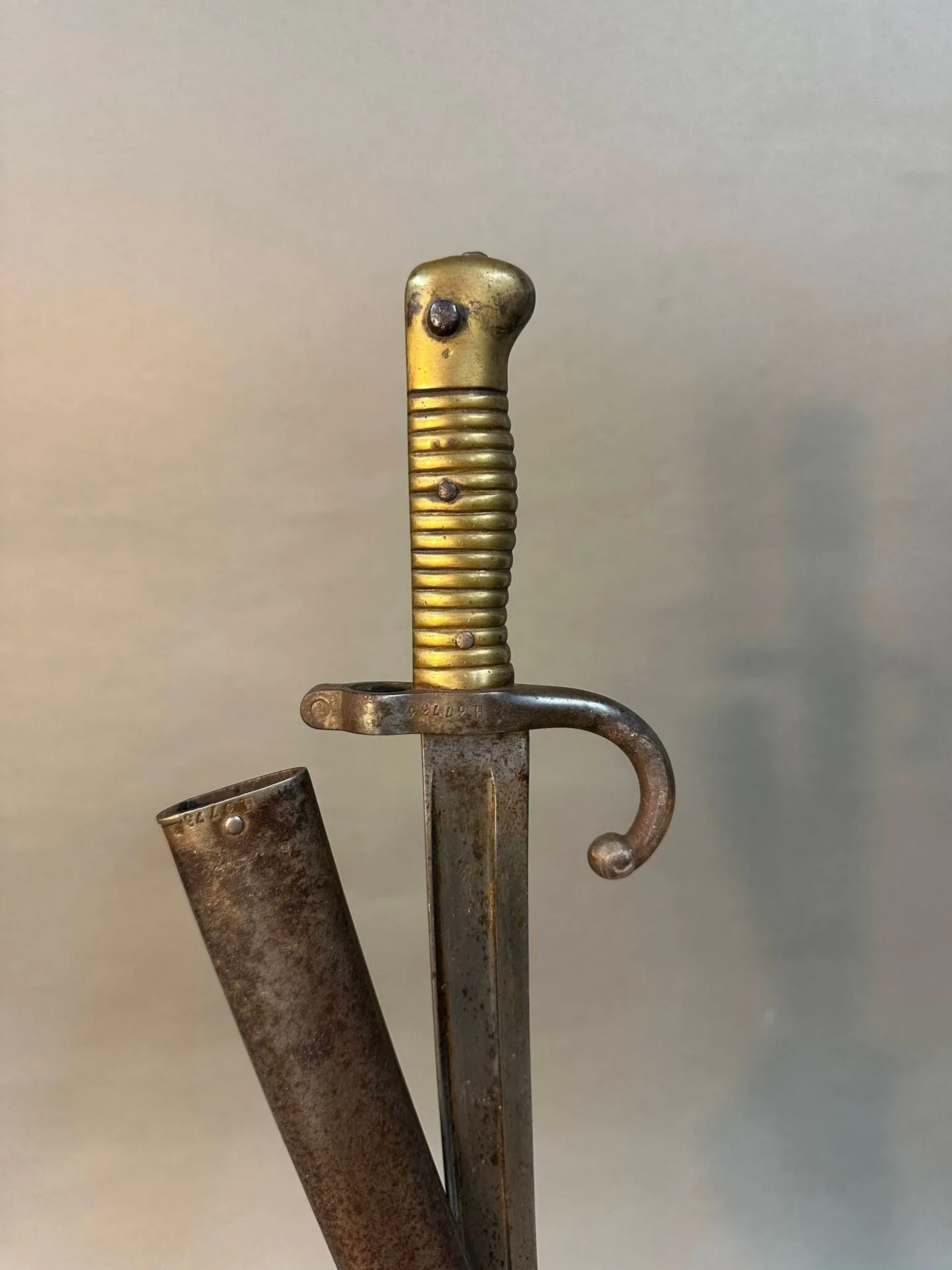 Baïonnette modèle 1866 pour fusil Chassepot. Monture en laiton et quillon fer. Lame à la yatagan de la manufacture Impériale de Mutzig, date 1858. Fourreau en acier au même numéro. Longueur totale: 69 cm. France, Époque Second Empire.