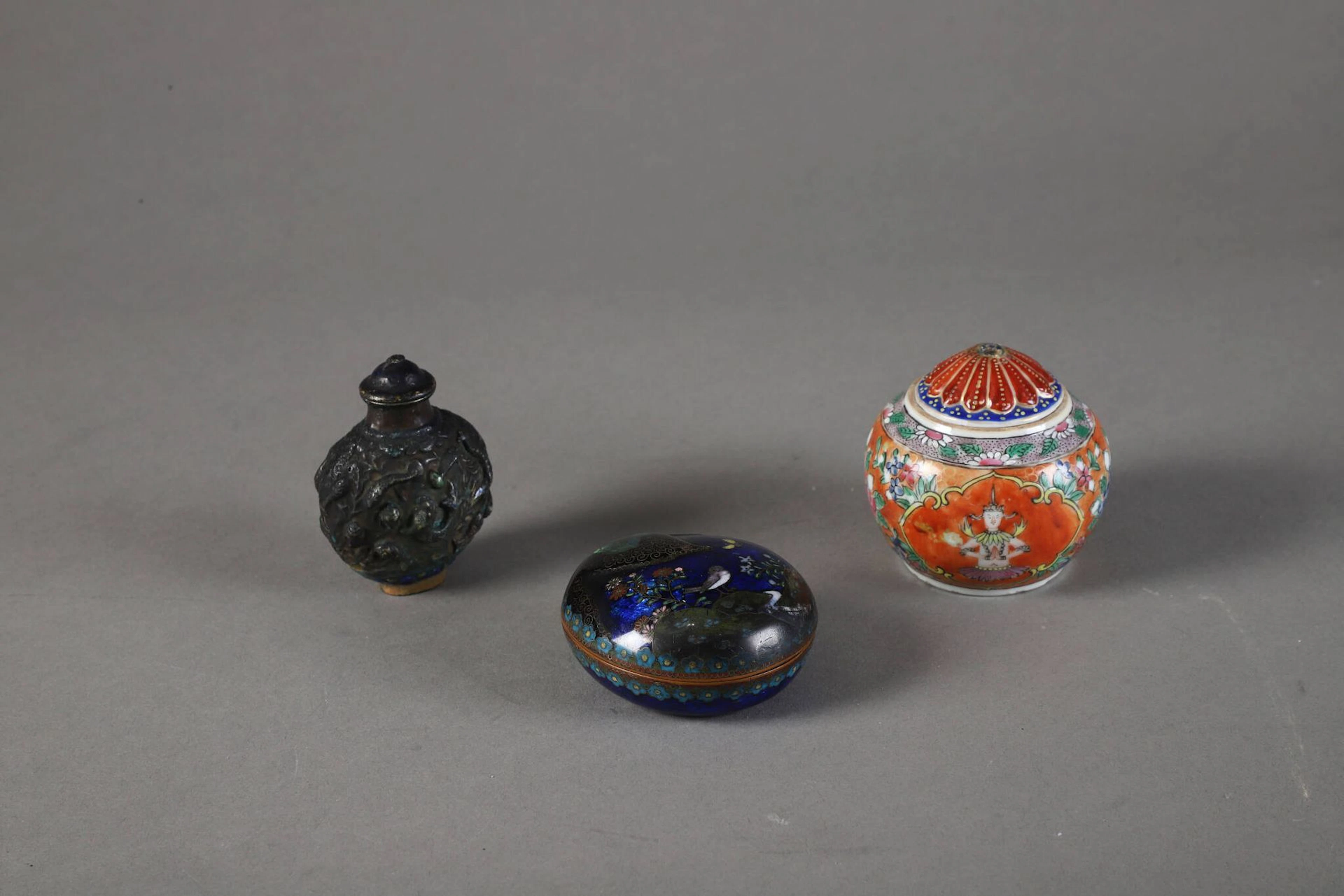 Lot composé : - CHINE, Bencharong, pour la Thaïlande - Fin XIXe siècle Bol couvert en porcelaine émaillée polychrome de theppanom en réserve. Accidents au couvercle. - CHINE, boite de forme ovoïde en émail cloisonné polychrome à décor d'oiseaux, papillons, fleurs dans un paysage. XXème siècle - Flacon tabatière à décor émaillé en relief de poissons, crabe, et coquillages. Chine, XXème siècle