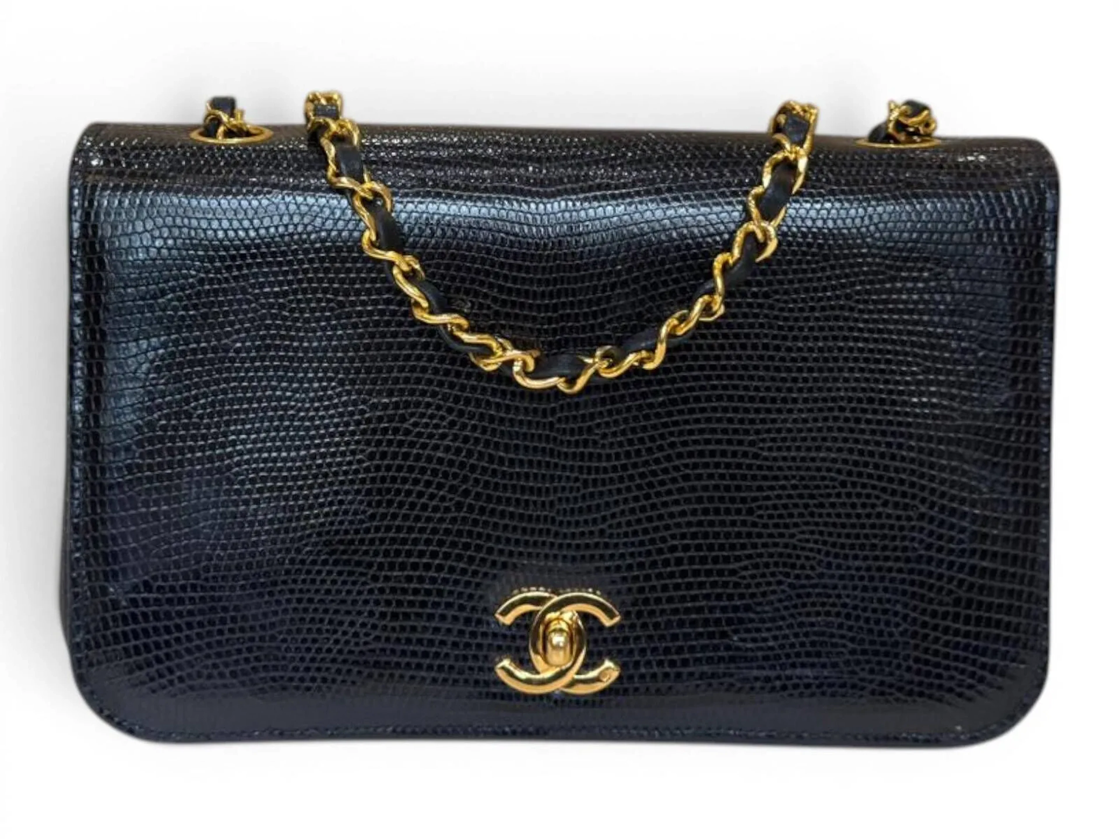 CHANEL Sac classique à rabat en lézard noir Doublure en agneau noir Bijouterie en métal plaqué or, bandoulière Fermeture par bouton pivotant Bon état, très légères traces d’usage dans les poches intérieures, étiquette d’authenticité, modèle de soldes Circa 1990 Dimensions : 23x14x7 cm environ