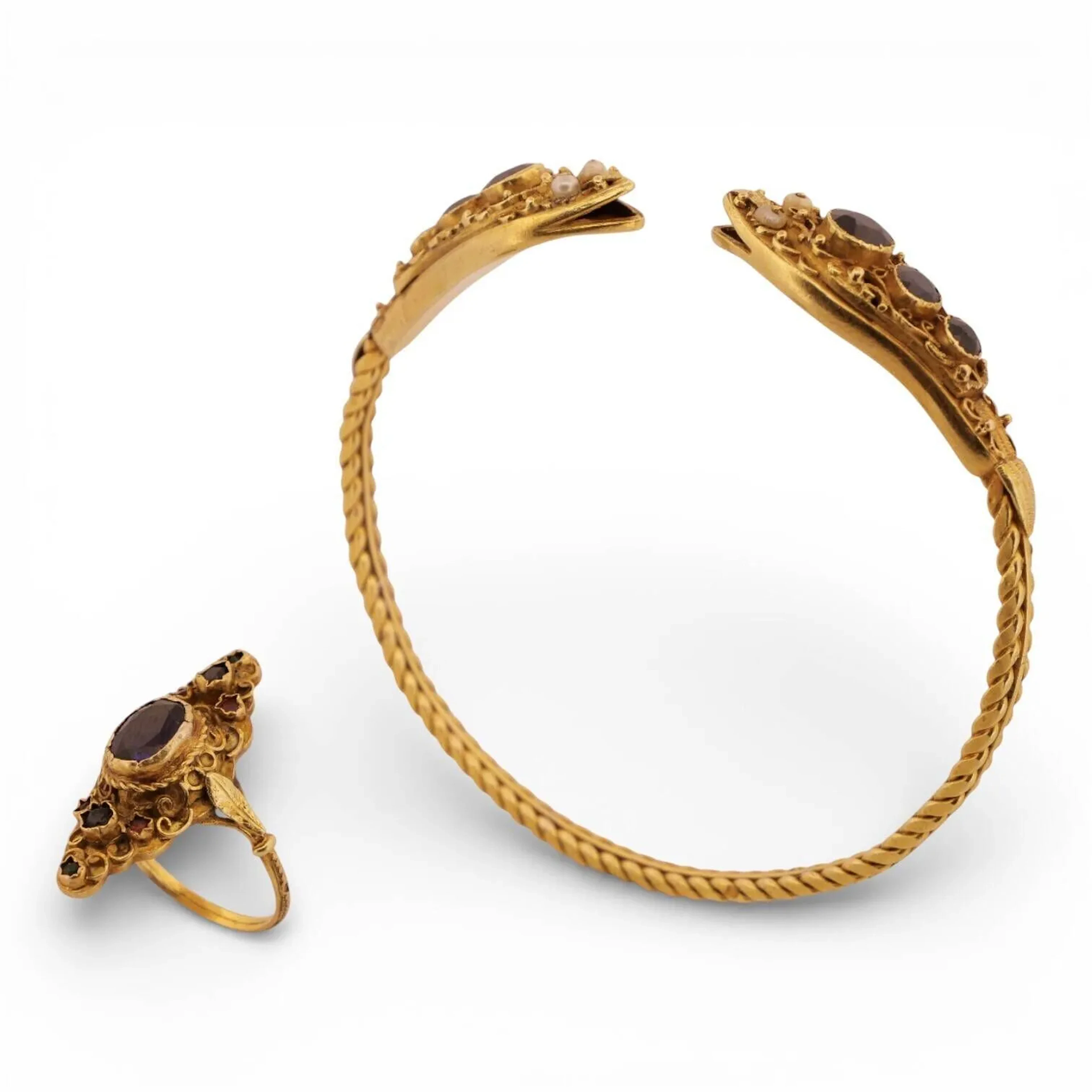Suite de deux bijoux en or 18K (750) comprenant : - un jonc ouvert à effet tressé, les extrémités formant une tête de serpent ouvragées de volutes, chacune sertie de trois diamants en chute. Les yeux piqués de petites perles. - une bague navette appliquée de volutes et sertie d'une pierre ovale bleue et de petites pierres bleues, roses et vertes. Tour de doigt : 56 Travail étranger. Poids brut total : 26.86 g.