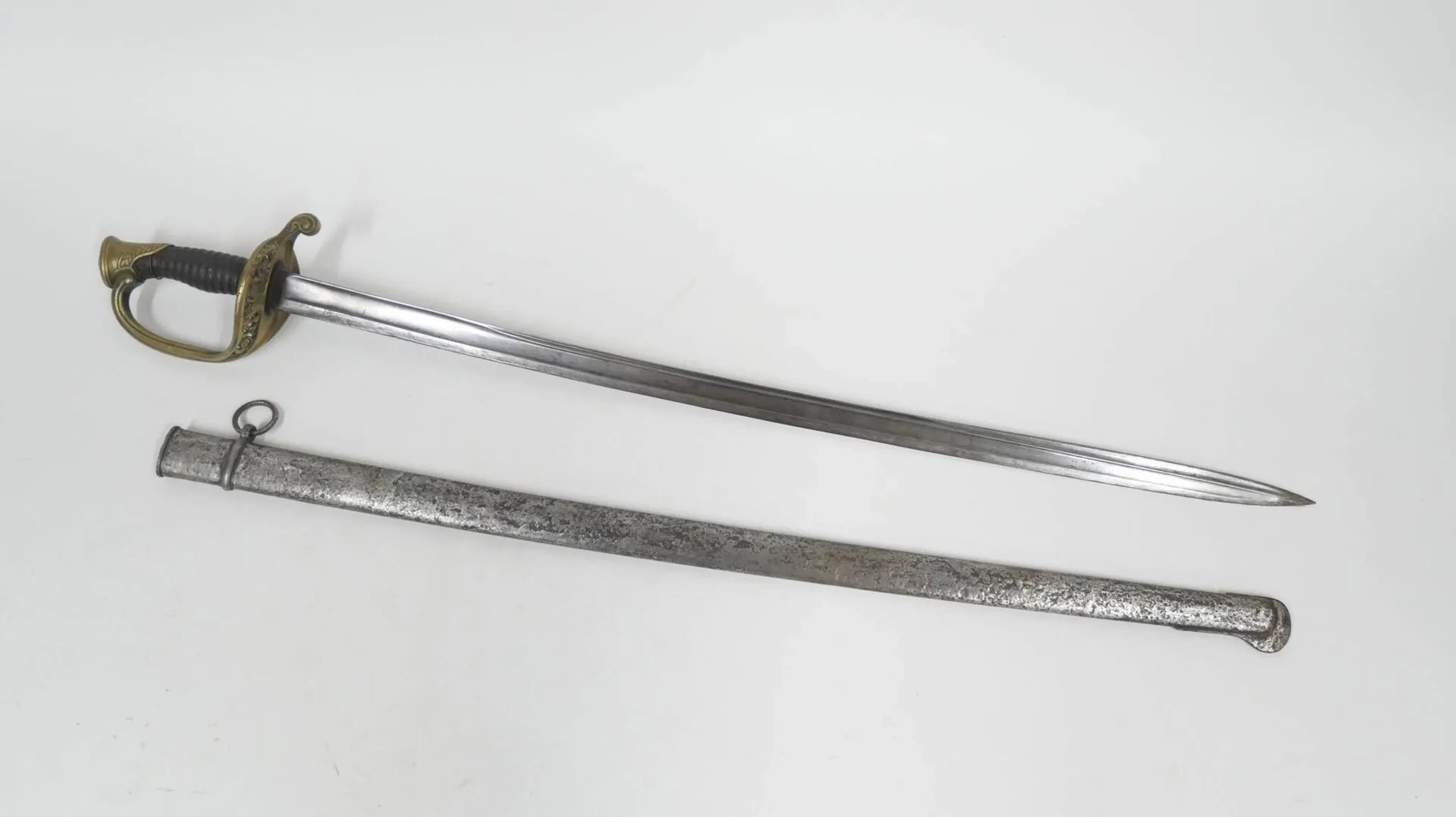 Sabre d’officier d’infanterie modèle 1855. Monture en bronze, calotte ciselée à la couronne, arc de jointure au filet, plateau ajouré à décor de fleur, quillon en forme de goutte. Fusée en corne, manque le filigrane. Lame légèrement courbe à gorge et gouttière marquée « Mre Nle de Chatelr mars 1871 o. d’Inft M 1845 ». Fourreau poinçonné à la chape en fer à un bracelet et anneau de suspente. Oxydations, en l’état. Longueur totale : 91 cm. France, époque IIIème République. La date de production de ce sabre correspond à la période de la commune de Paris.