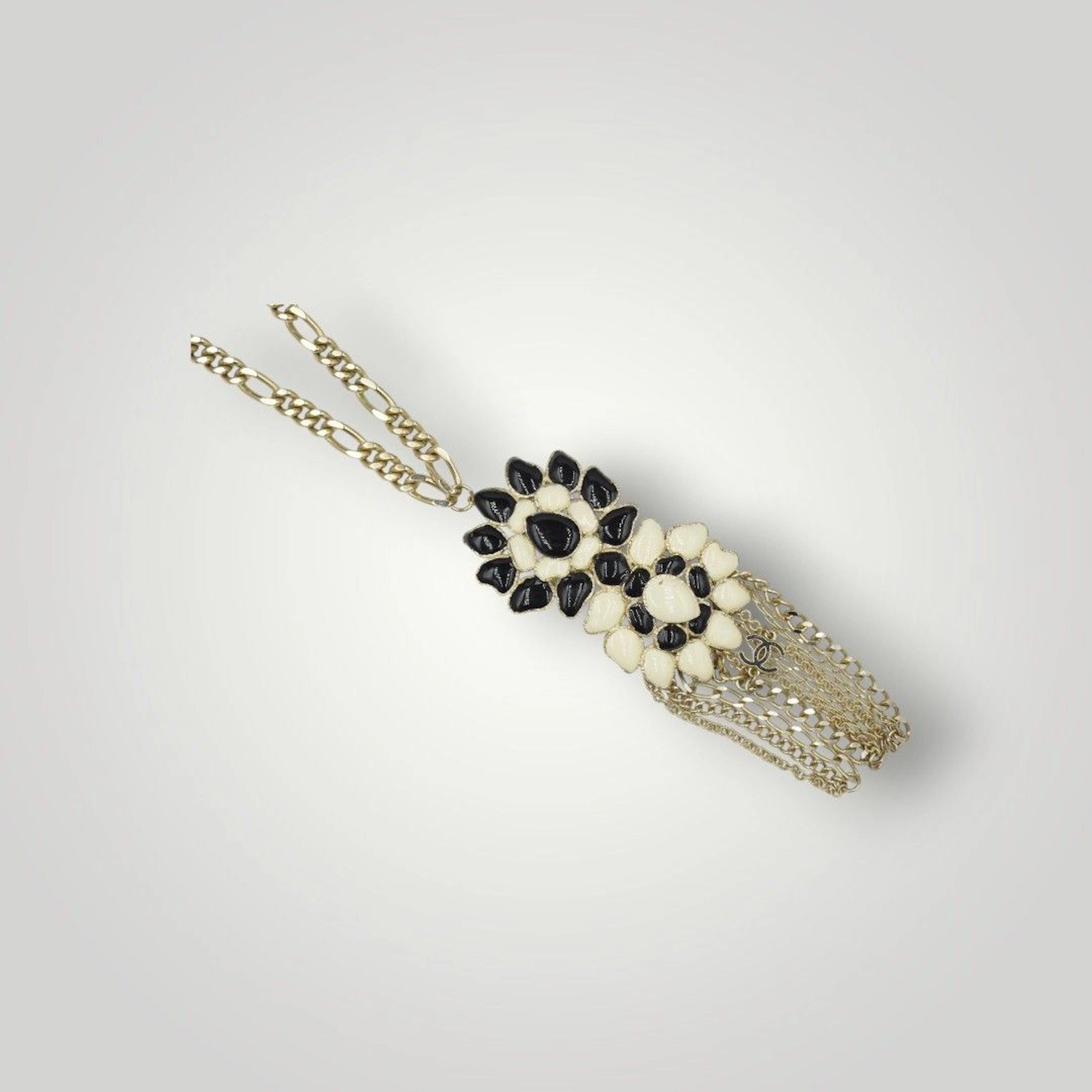 CHANEL par Karl LAGARFELD (1983-2019) et GRIPOIX Collier retenant un motif de fleurs en pâte de verre noire et ivoire à pampilles multichaînes. Non signé Long totale : 58 cm ; Haut. du motif: 14,5 cm Petits défauts de cuisson et petites oxydations, petites usures à la dorure